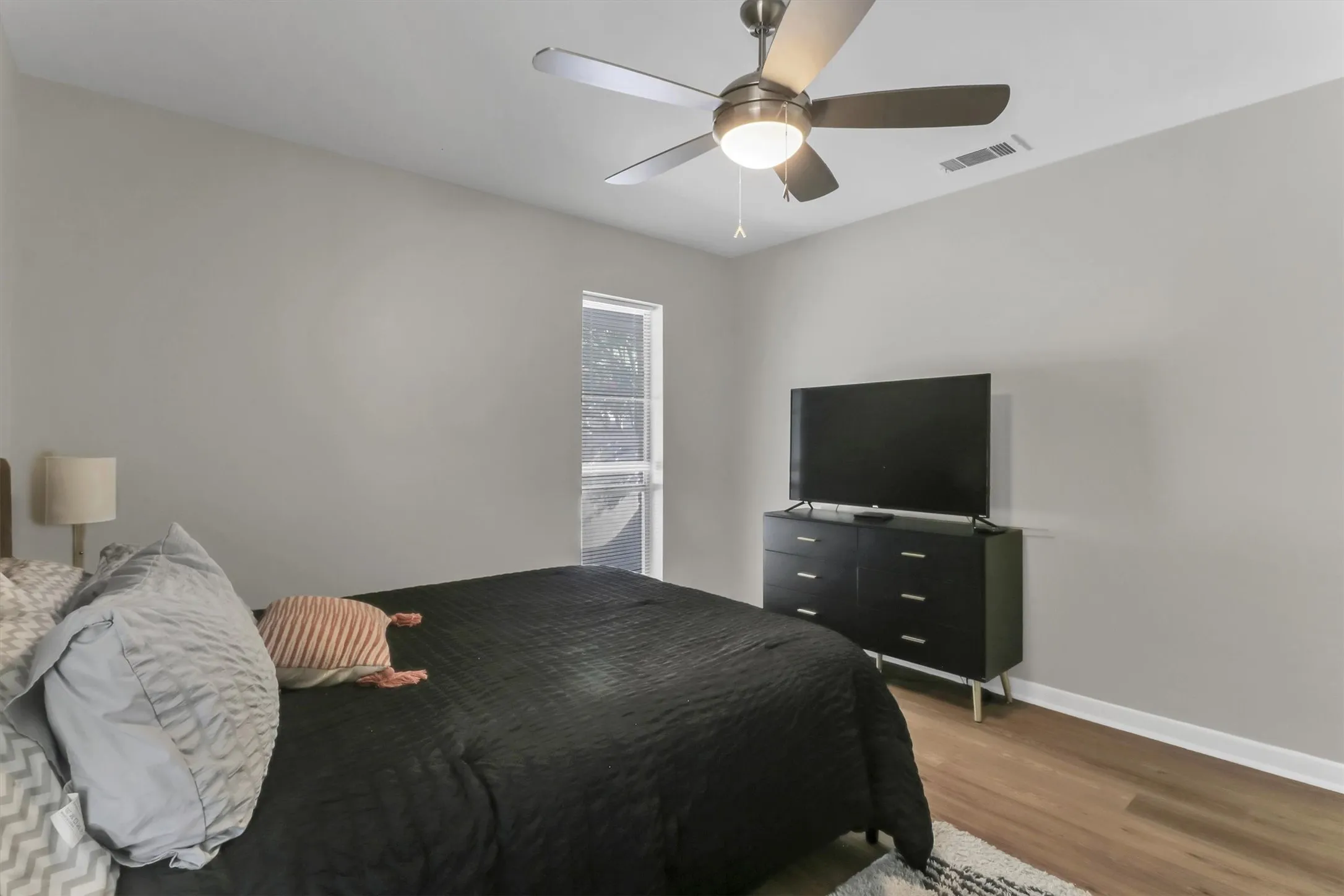 Interior room featuring light gray wall paint, wood-finish flooring, and white baseboards
