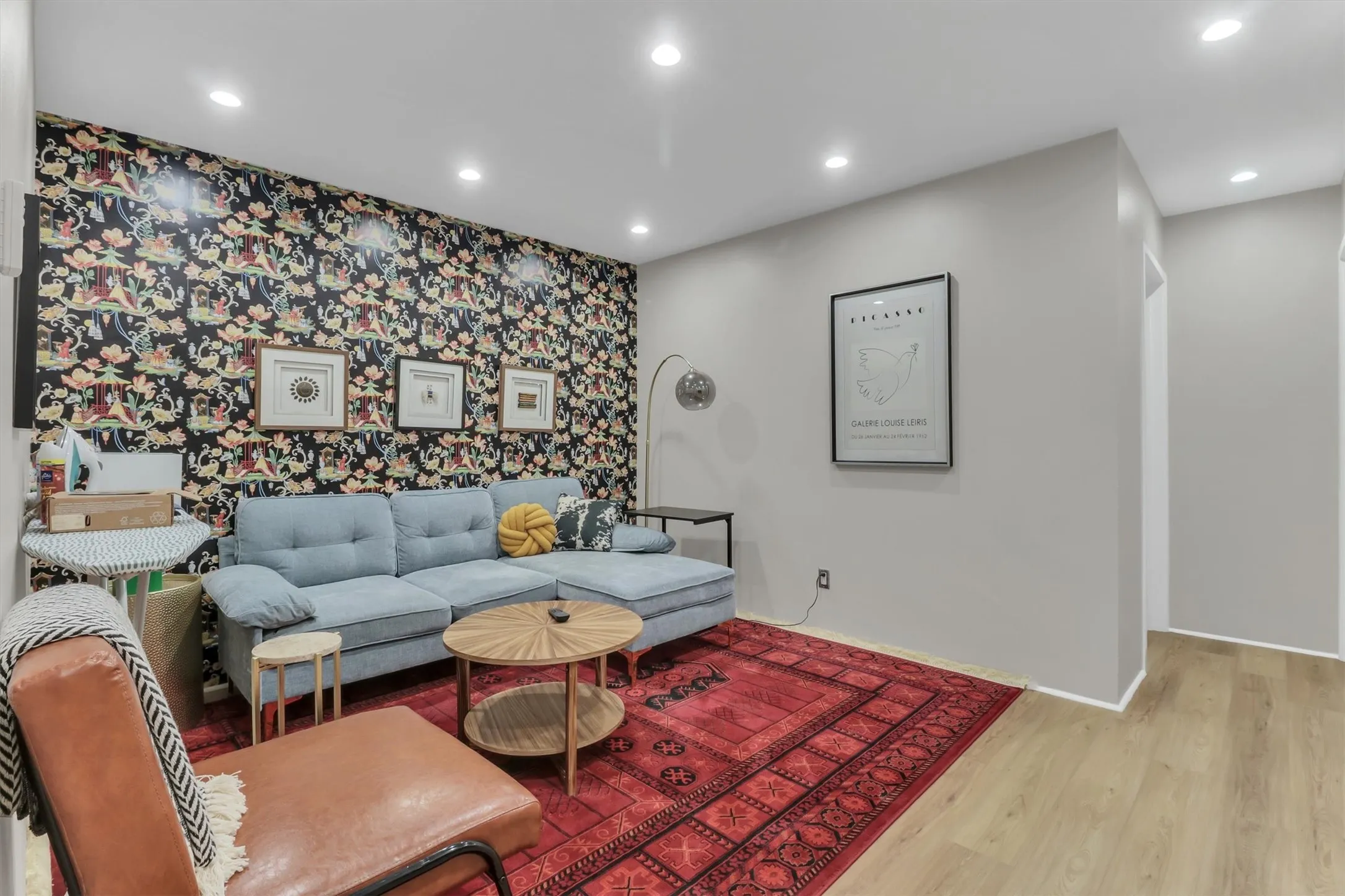 Recessed lighting illuminates a space featuring a prominent accent wall with patterned wallpaper
