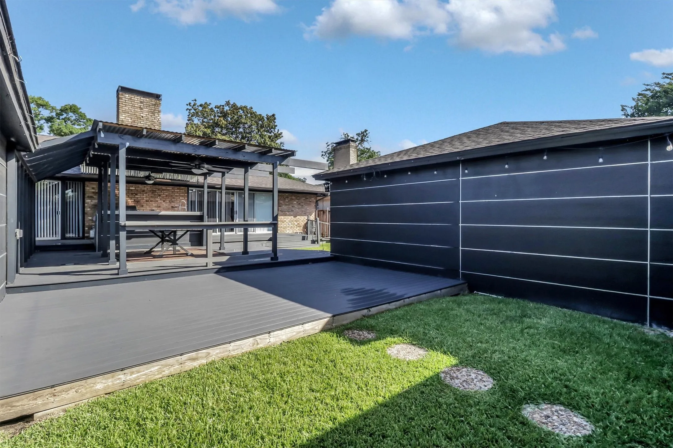 Expansive outdoor deck featuring a covered pergola, integrated bar counter, and dark composite decking