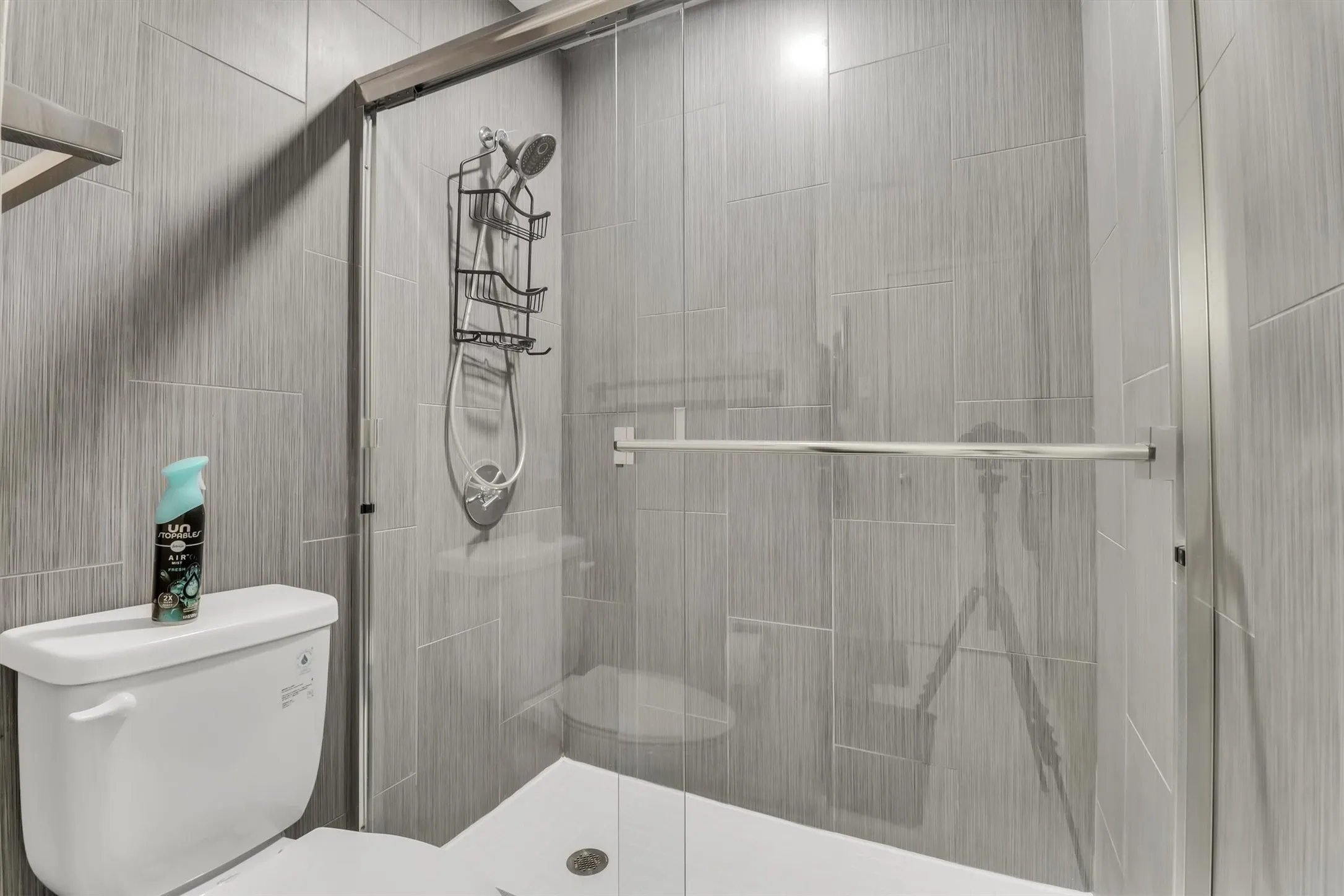 Full-height tiled shower with a glass enclosure and a hand-held showerhead