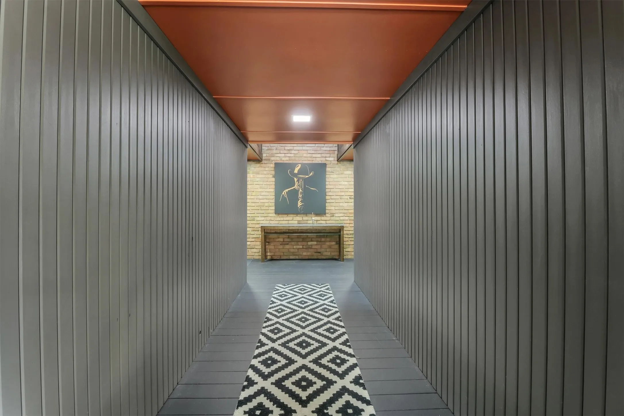 Hallway featuring vertical slat wall panels, wood-finish flooring, and a flat ceiling