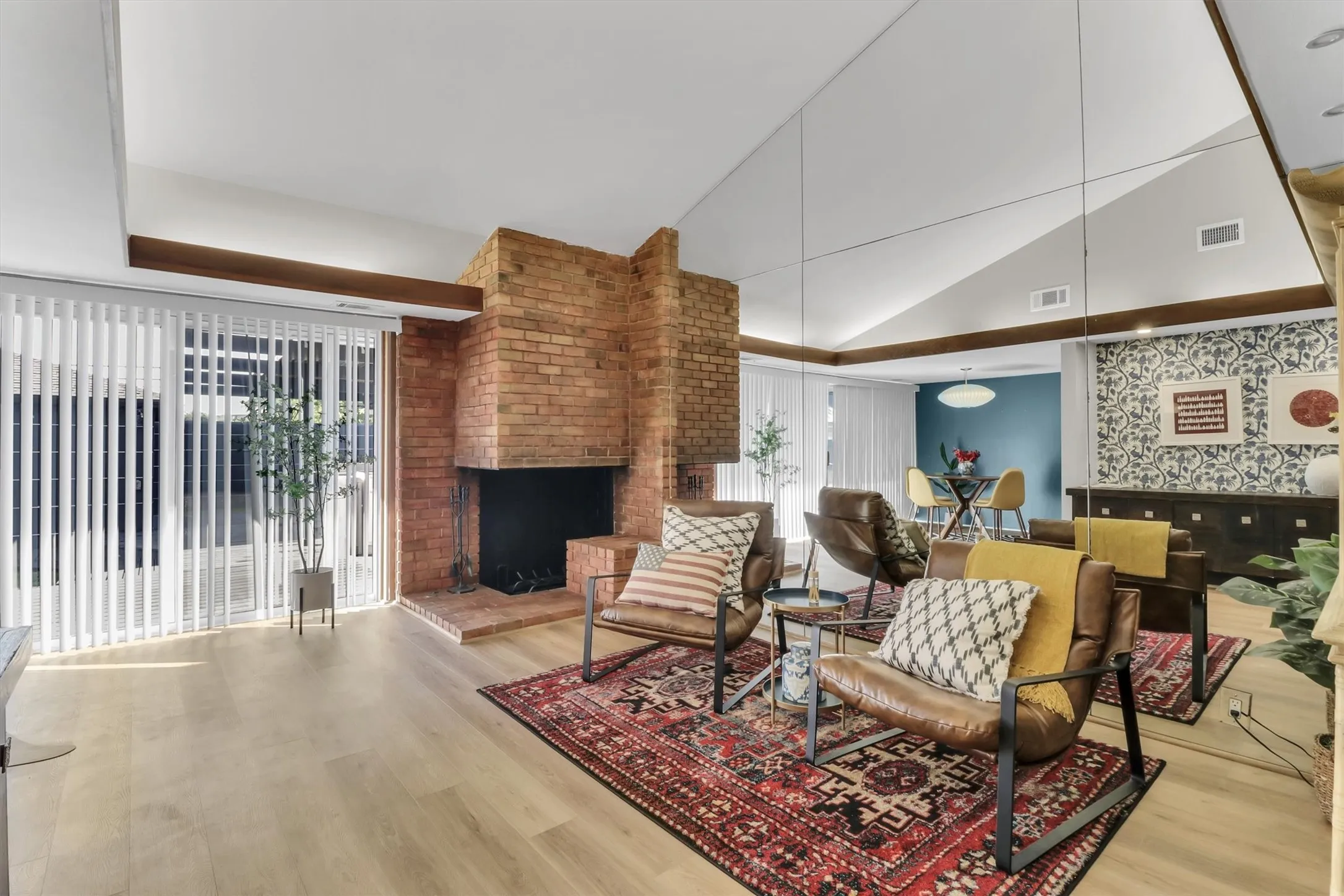 Living area featuring a brick fireplace, wood-finish flooring, and a vaulted ceiling