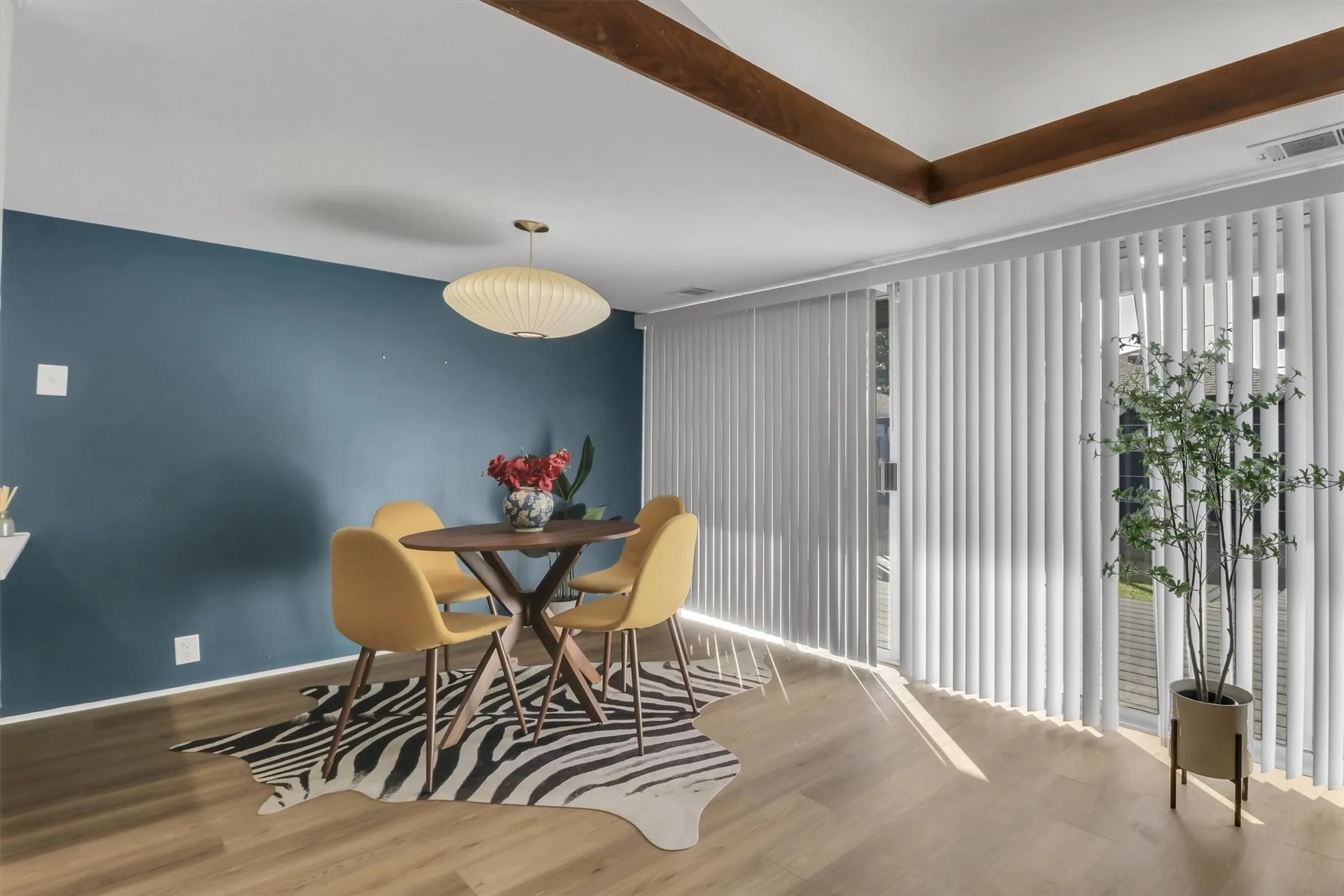 Bright interior space with wood-finish flooring, a vibrant accent wall, and exposed wooden ceiling beams