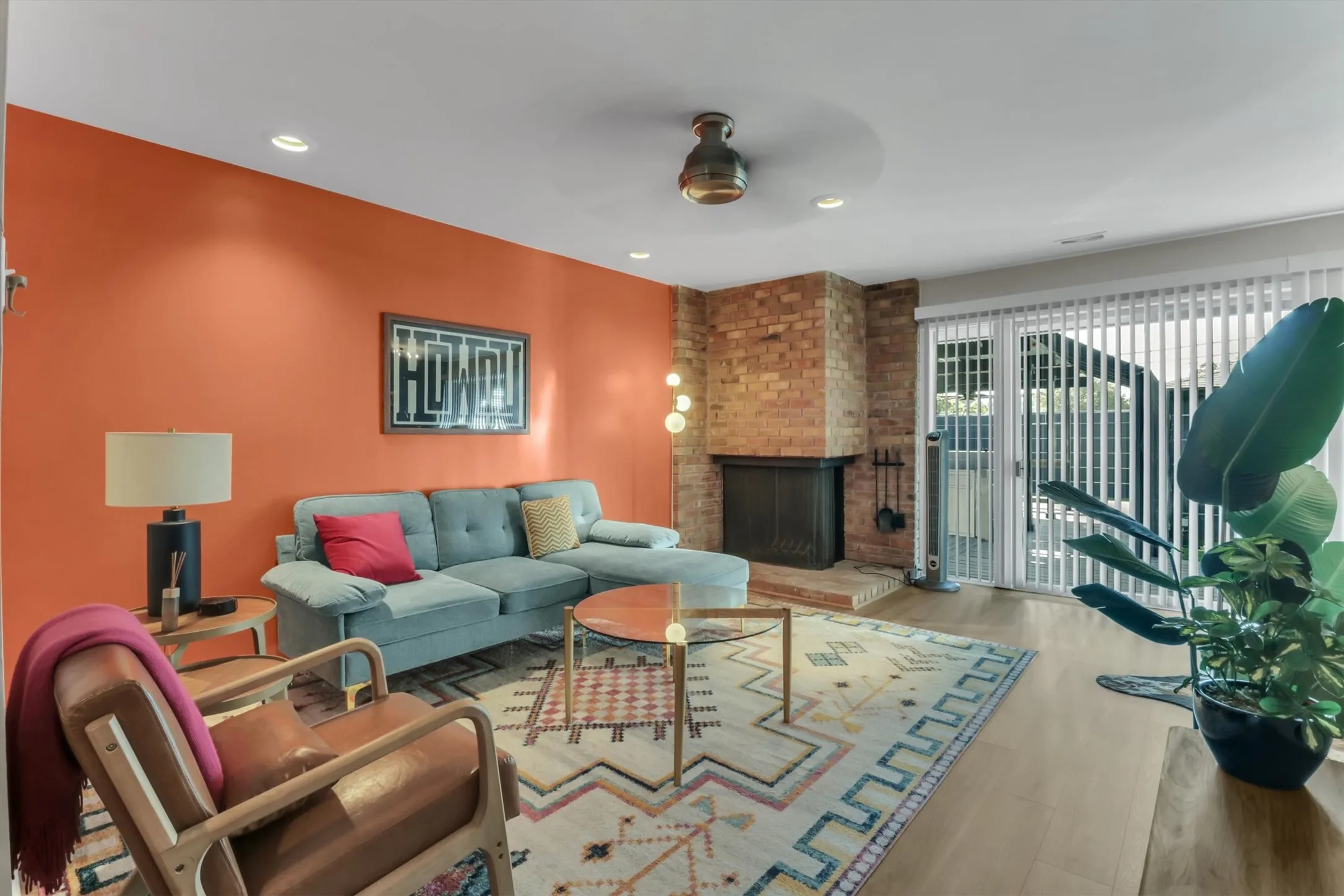 Spacious living area featuring a brick-surround fireplace, wood-finish flooring, recessed lighting, and a ceiling fan