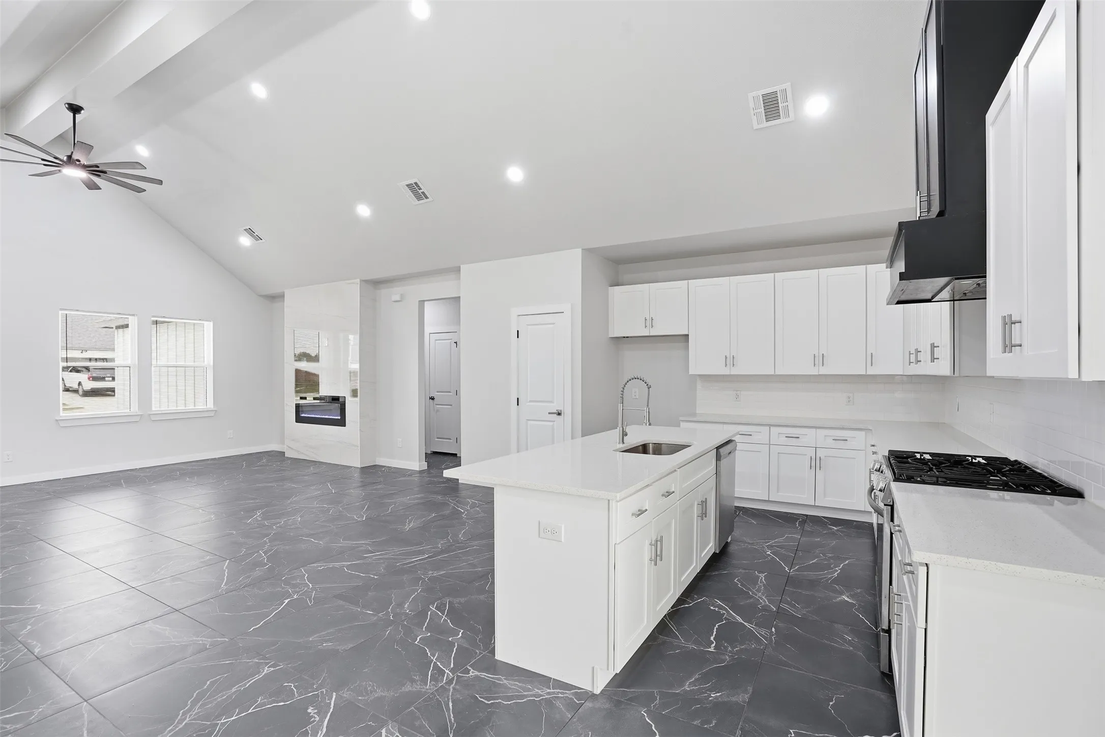 Open concept living space featuring vaulted ceilings, recessed lighting, and large format gray floor tiles