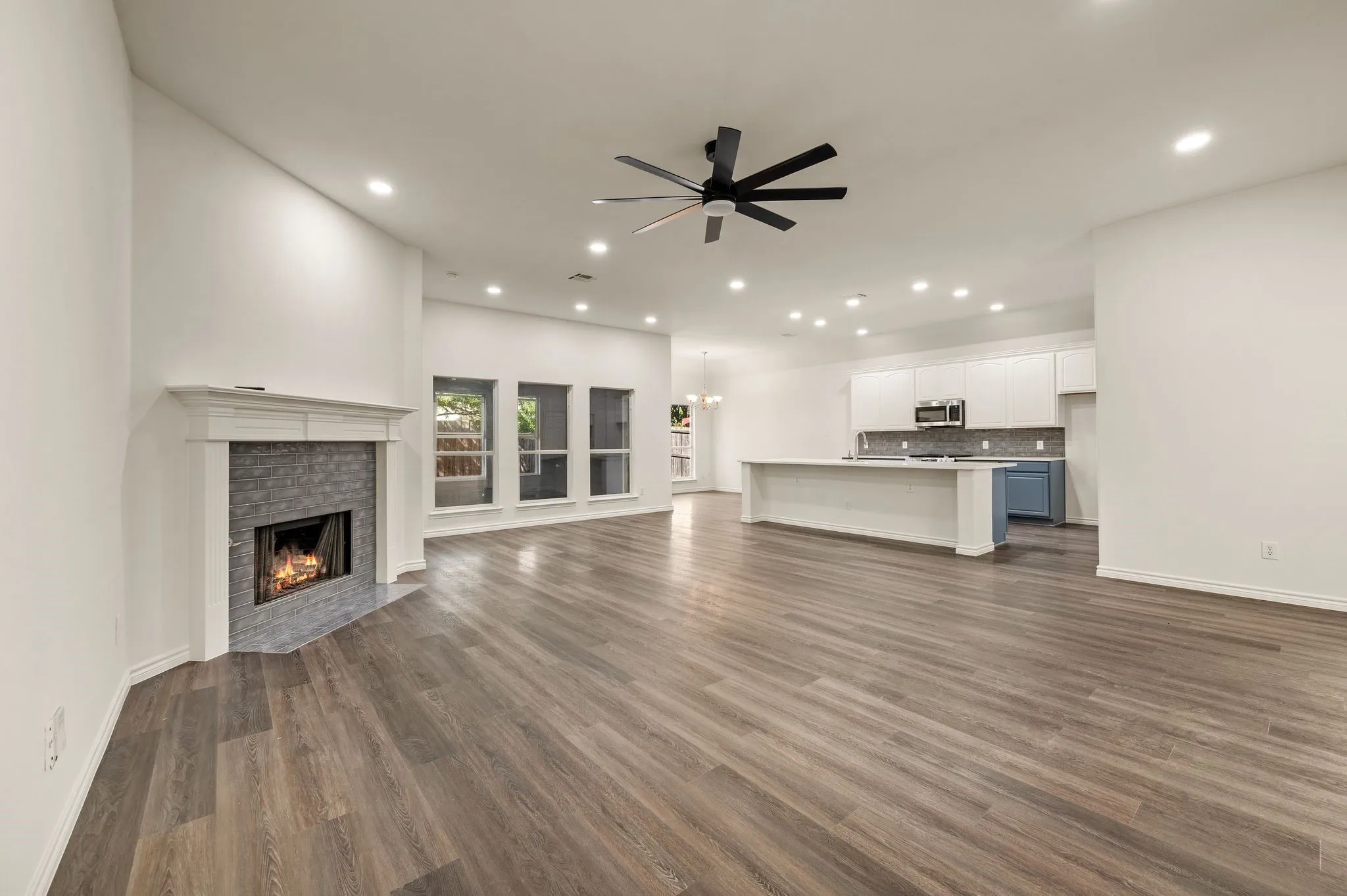 Open-concept living space featuring wood-finish flooring throughout, recessed ceiling lighting, and a modern ceiling fan with black finish