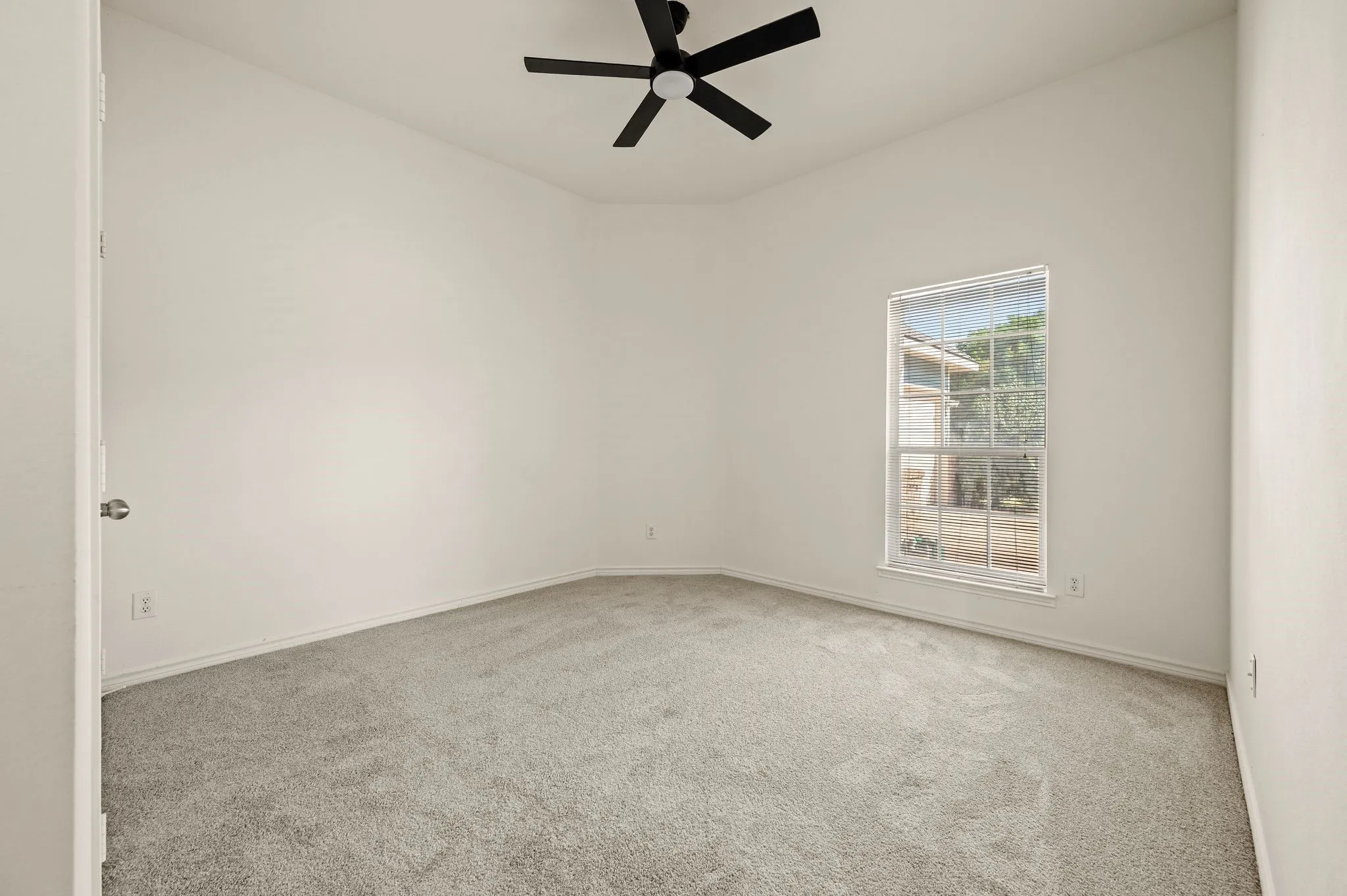 Neutral wall color, carpet flooring, window with exterior scenery, ceiling fan, and sloped ceiling