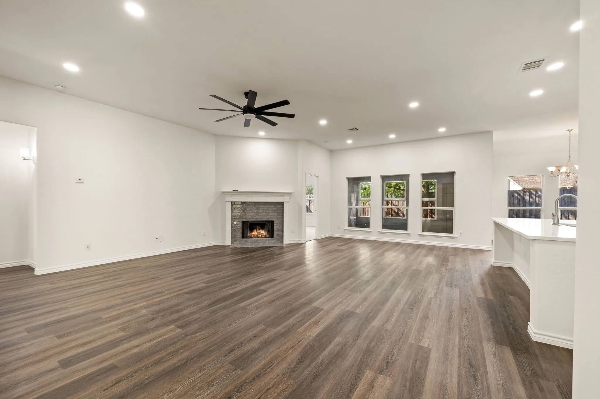 Spacious open-concept living area featuring wood-finish flooring throughout, recessed lighting, and a ceiling fan