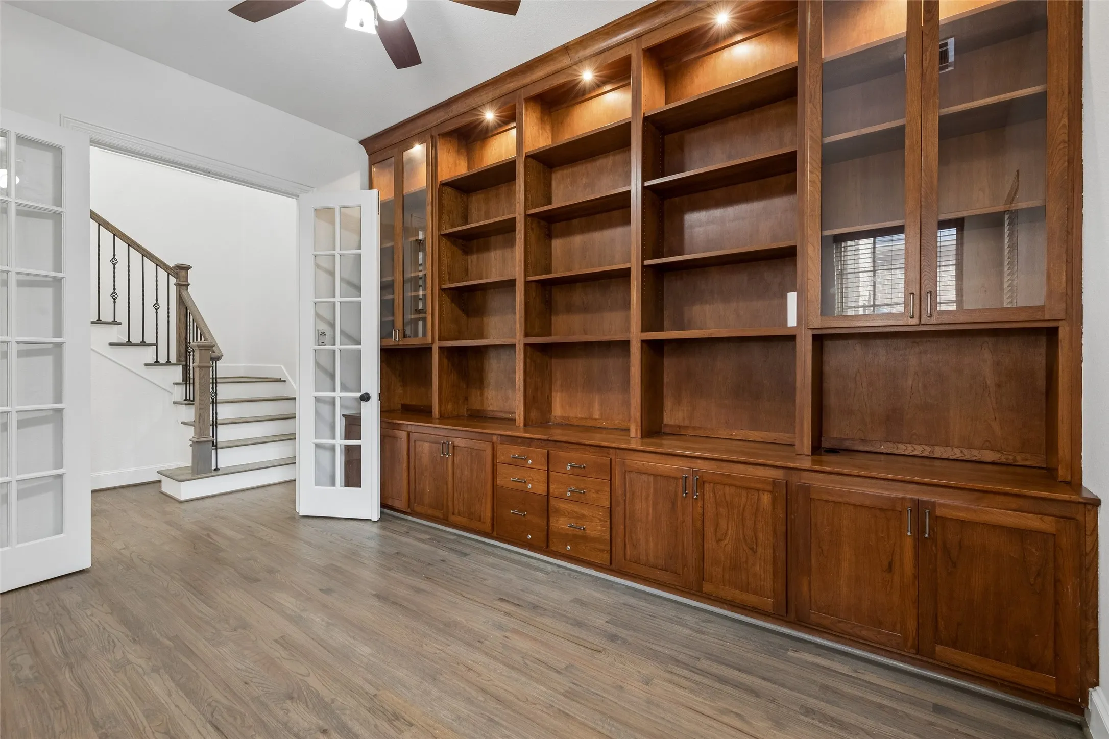Office with French doors, built in shelving, and refinished hardwood floors.