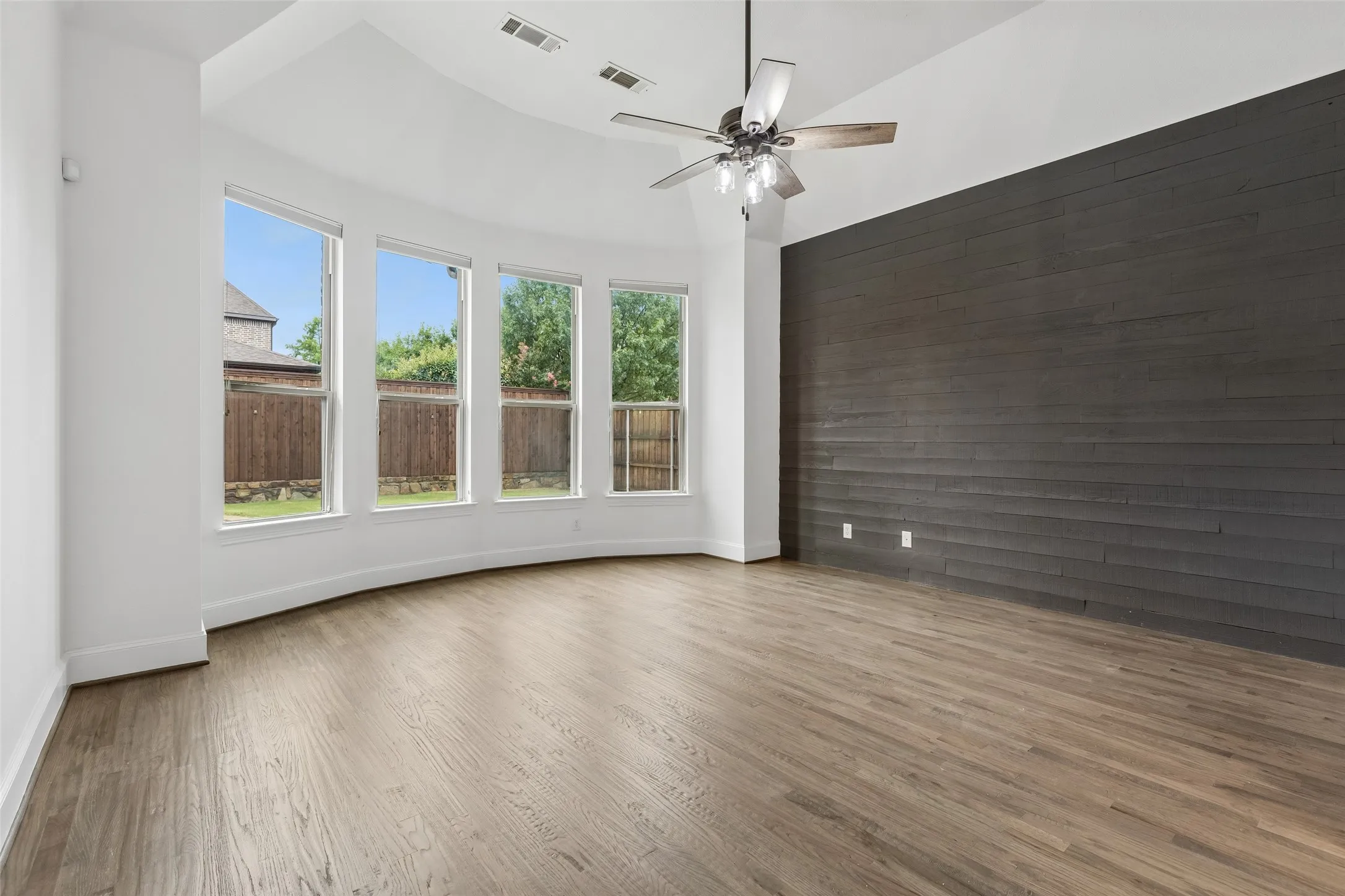 Primary bed room with refinished hardwood floors, bay windows, custom accent wall, and renovated en suite bathroom and walk in closet.