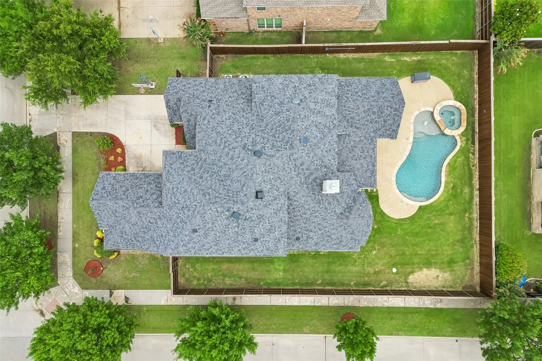Overhead aerial view of corner lot, pool & spa, extended covered patio, and large grass area.