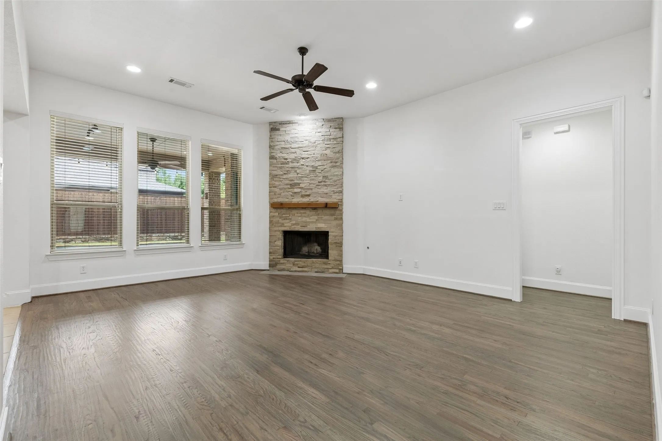 Living room with refinished hardwood floors and floor to ceiling stacked stone gas fireplace.