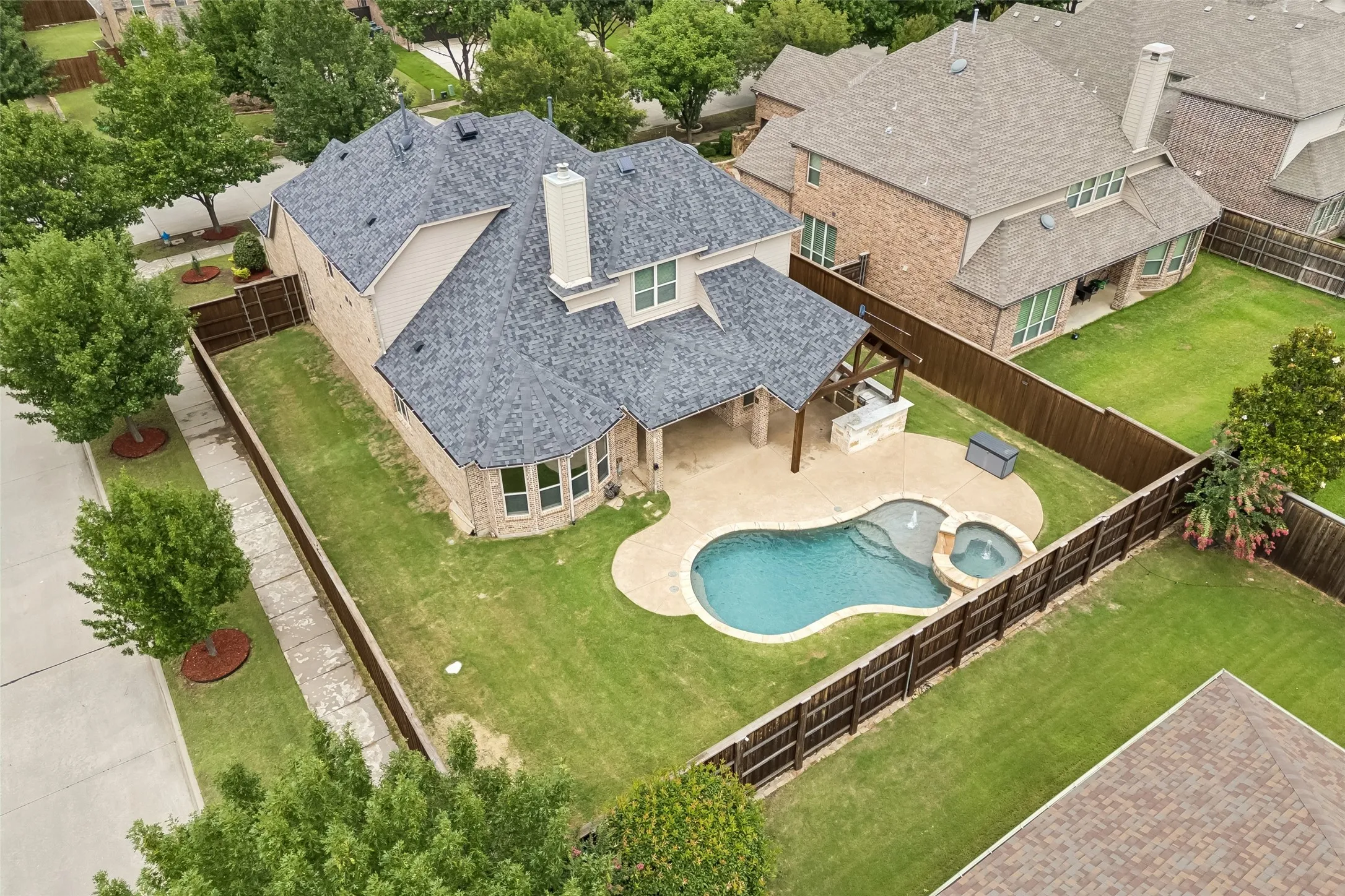 Back yard aerial view of corner lot, pool & spa, extended covered patio with built in outdoor kitchen & large grass area.