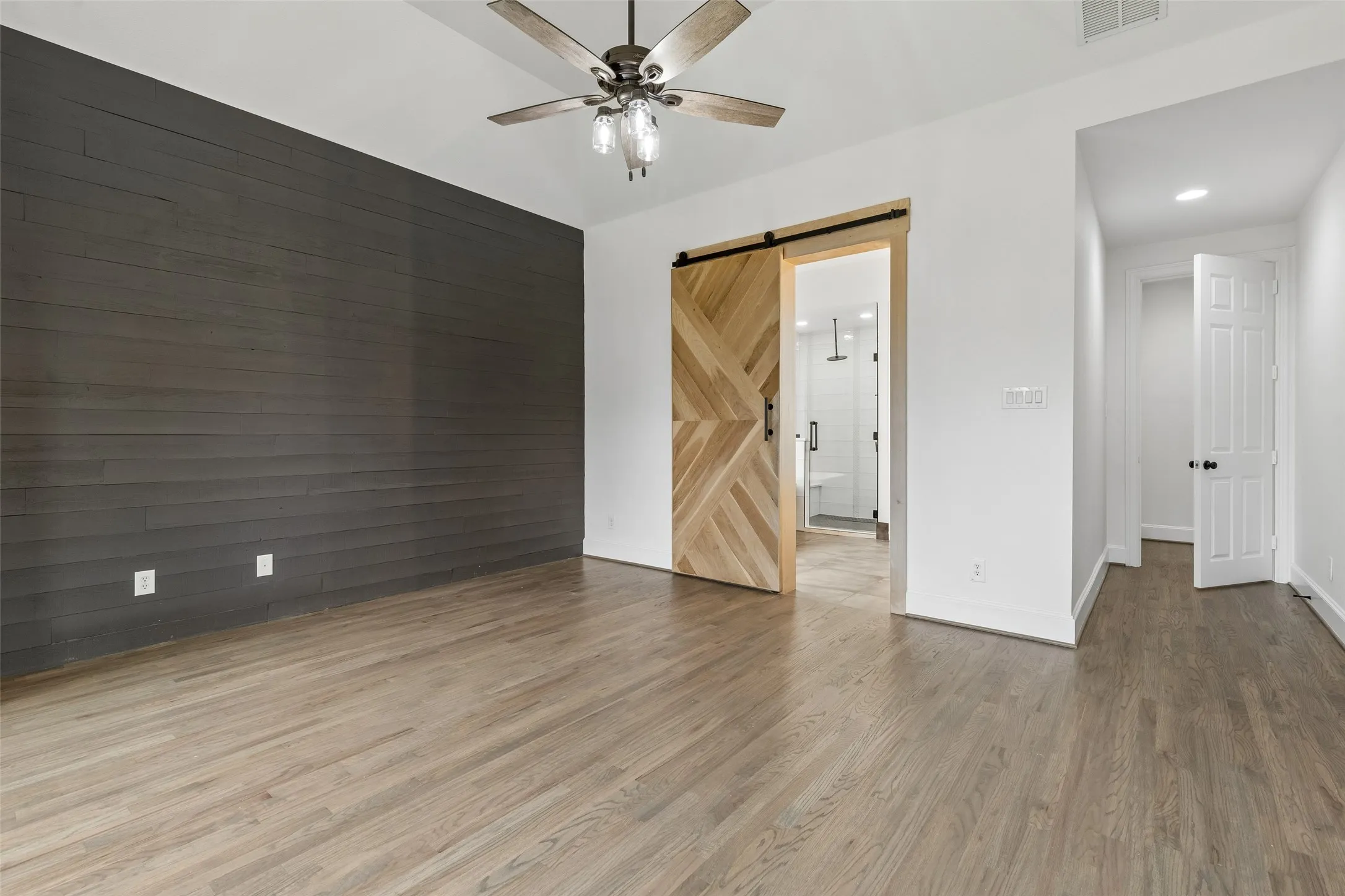 Primary bed room with refinished hardwood floors, bay windows, custom accent wall, and renovated en suite bathroom and walk in closet.
