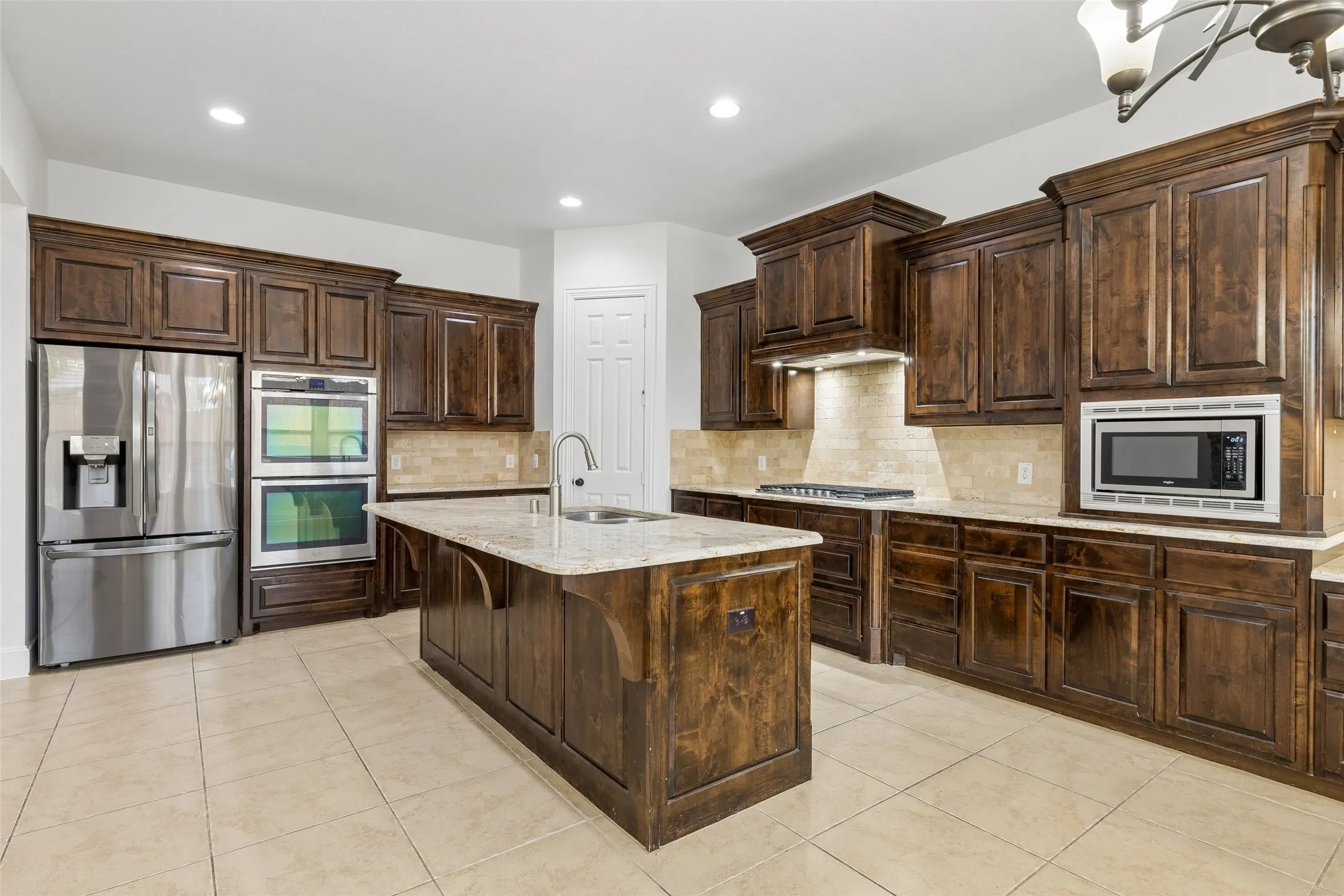 Kitchen with granite counter tops, tile backsplash, SS appliances, oversized kitchen island, planning desk, and walk in pantry.
