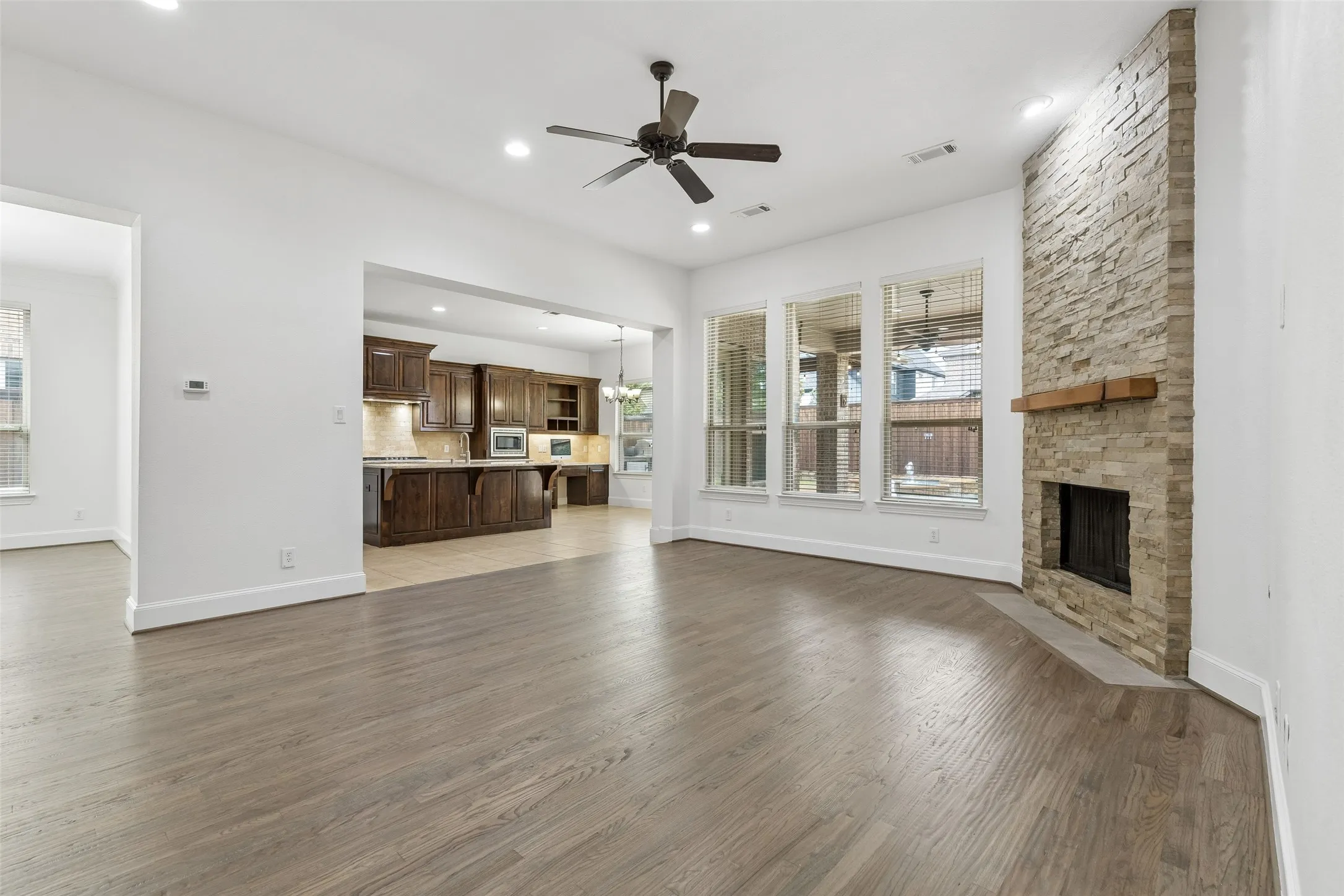 Living room with refinished hardwood floors and floor to ceiling stacked stone gas fireplace.