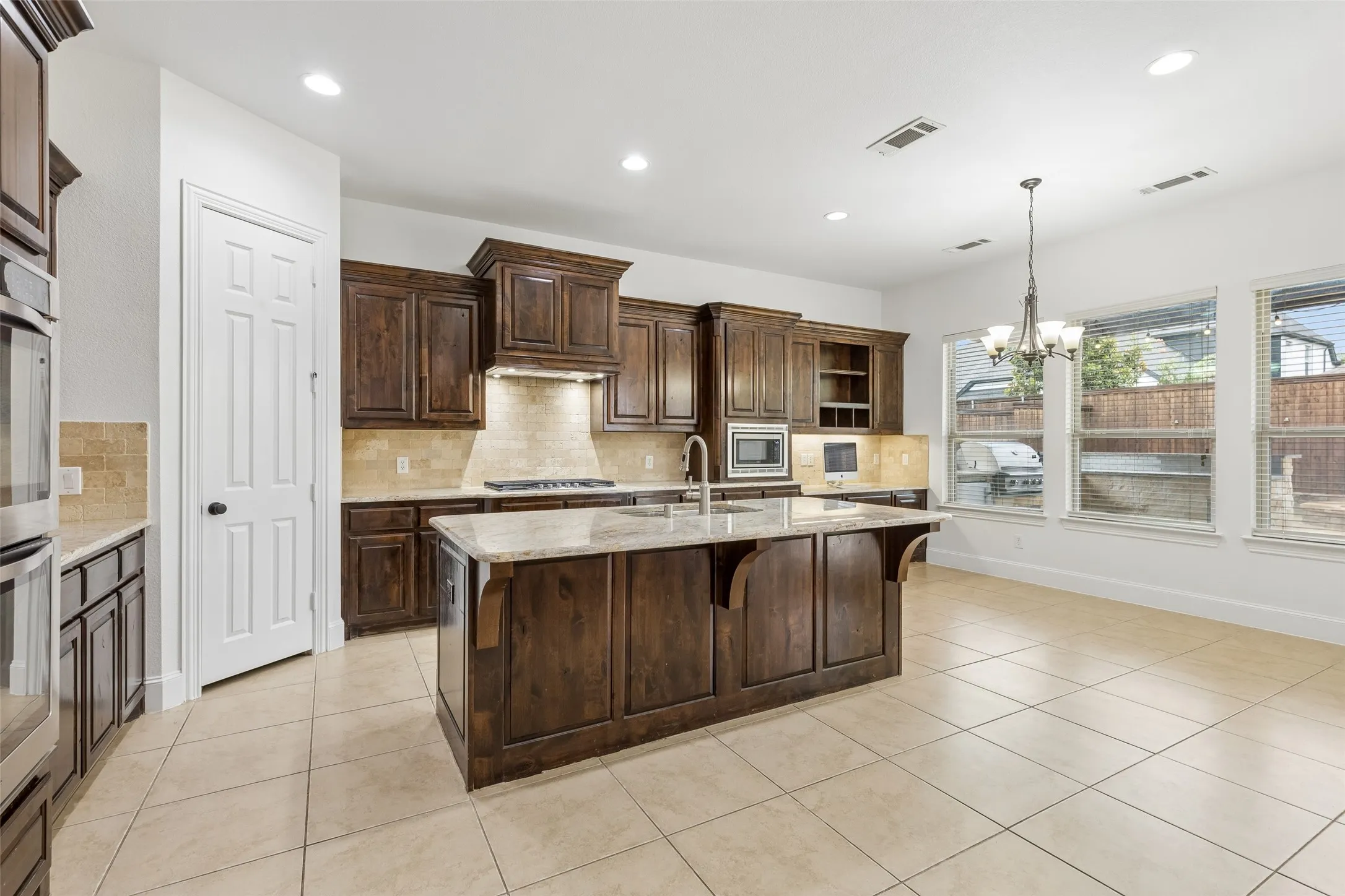 Kitchen with granite counter tops, tile backsplash, SS appliances, oversized kitchen island, planning desk, and walk in pantry.