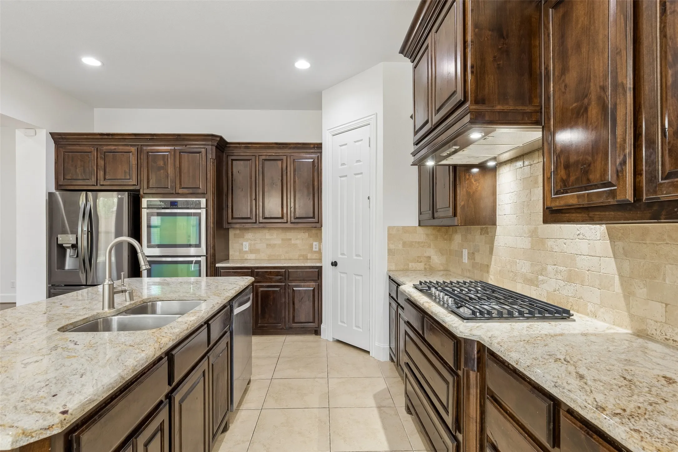 Kitchen with granite counter tops, tile backsplash, SS appliances, oversized kitchen island, planning desk, and walk in pantry.