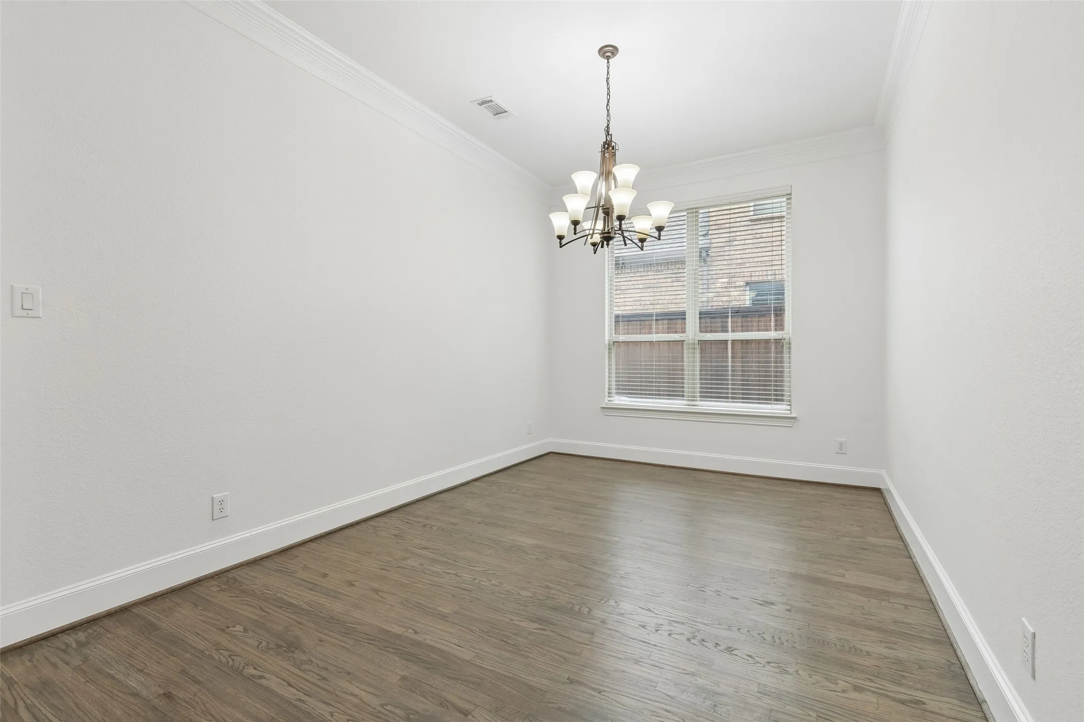 Dining room with refinished hardwood floors & crown molding.