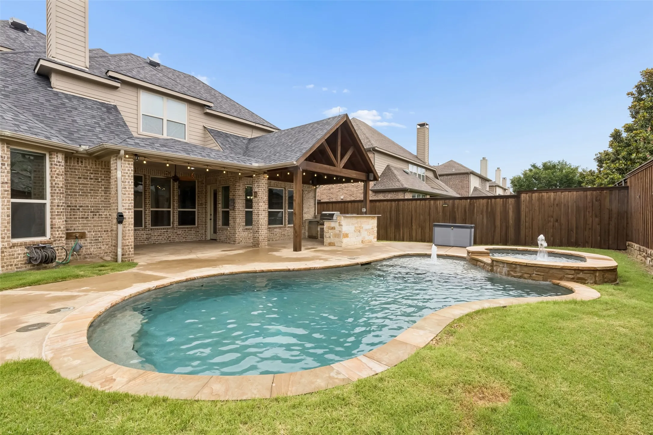 Back yard view of pool & spa & extended covered patio with built in outdoor kitchen.