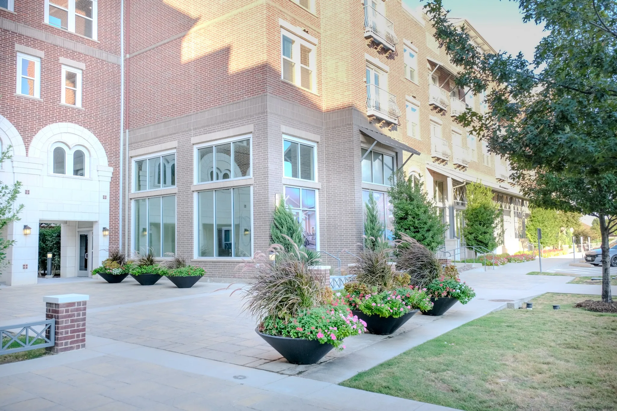 Brick and stone facade building featuring large windows, multiple balconies, and decorative planters