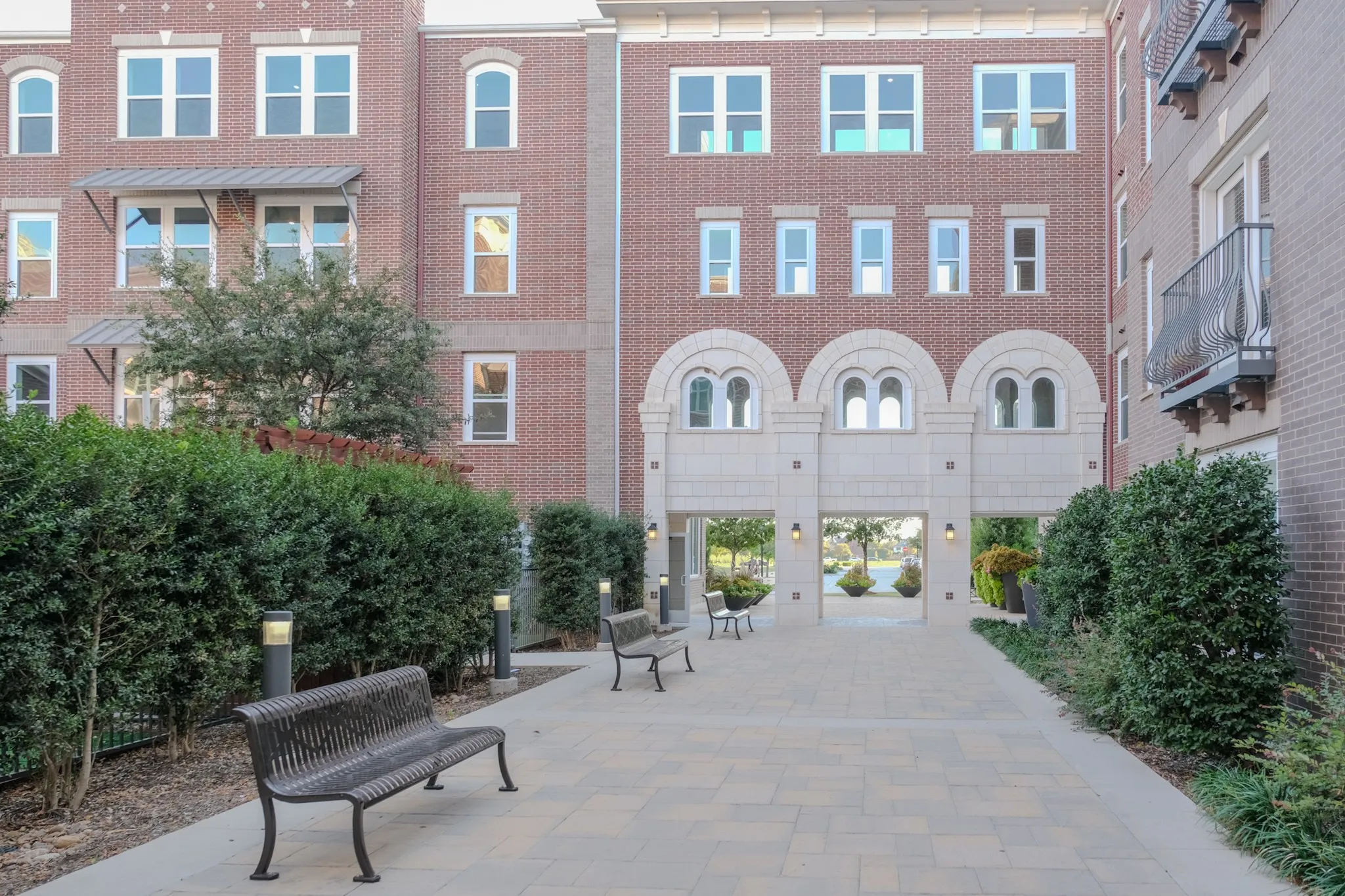 Expansive paver courtyard featuring architectural archways and integrated outdoor lighting