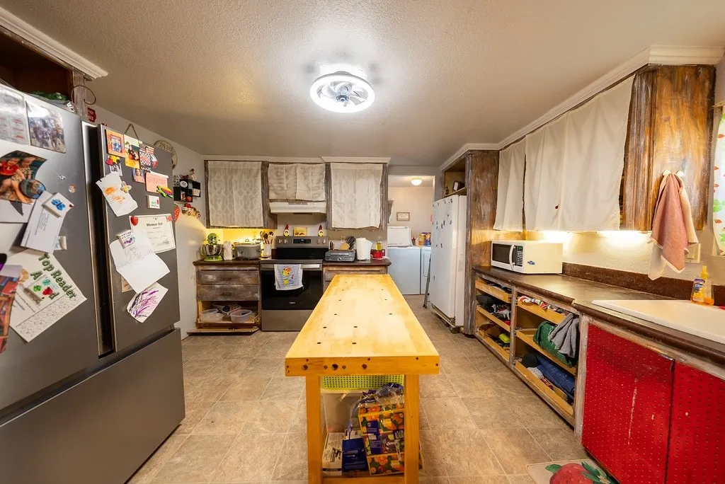 Kitchen featuring a range and a stainless steel refrigerator with an island