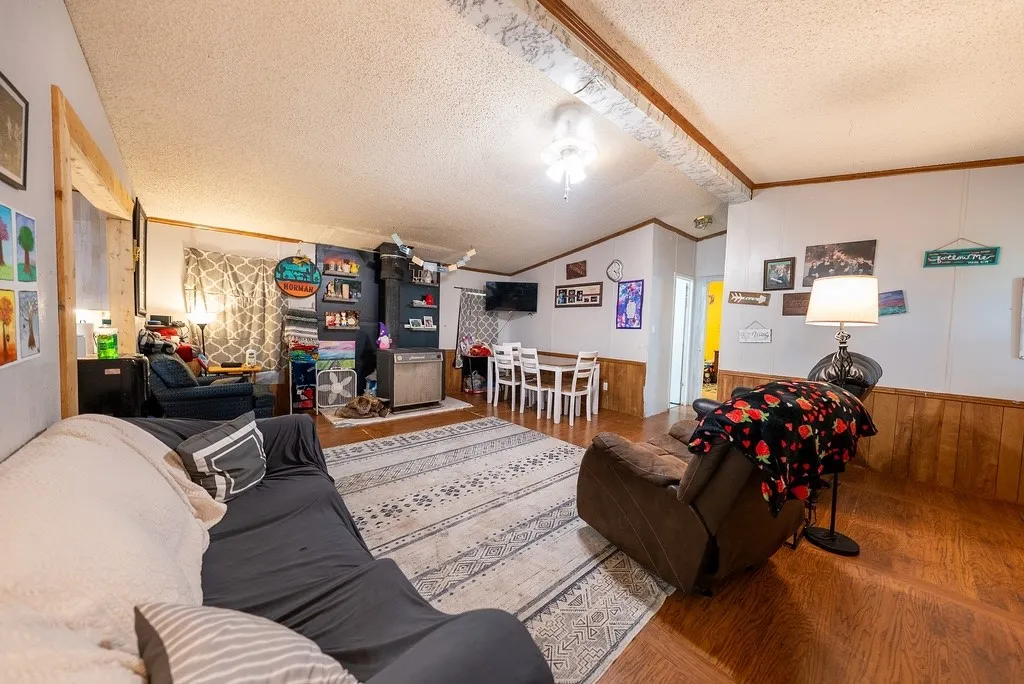 Open-concept living area featuring wood-finish flooring, white walls with wood paneling, and a dining space