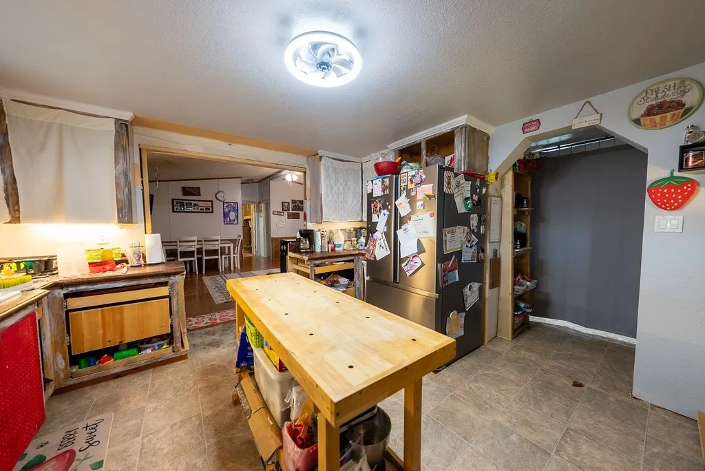 Kitchen featuring neutral-toned tile flooring, lighting, and a stainless steel refrigerator