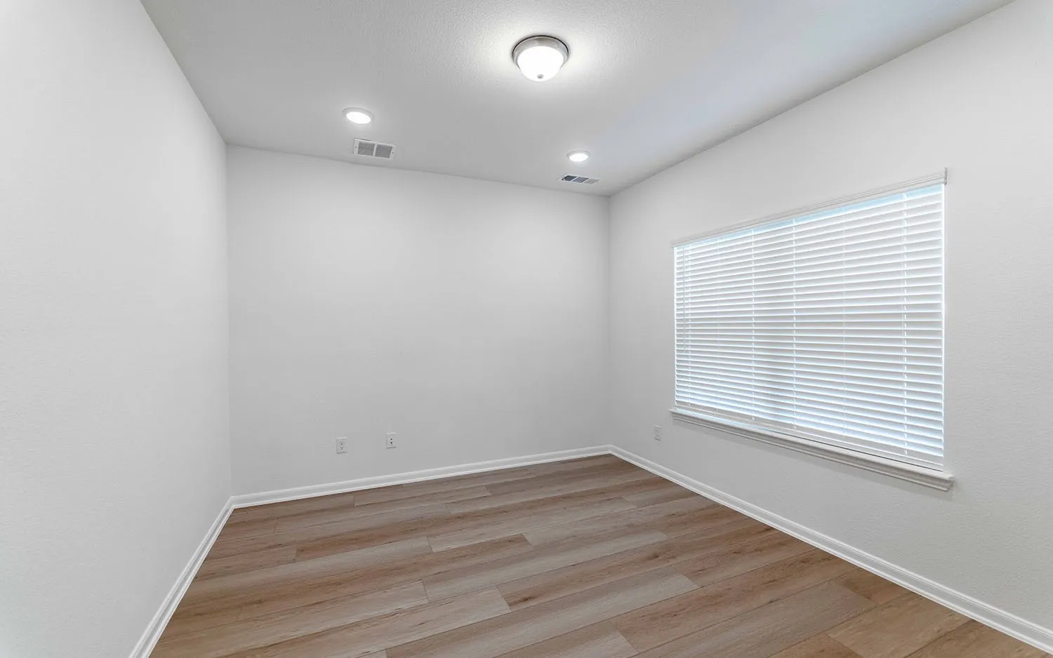Room featuring wood-finish flooring, white baseboards, a white window frame with blinds, recessed ceiling lights, and a central ceiling light fixture