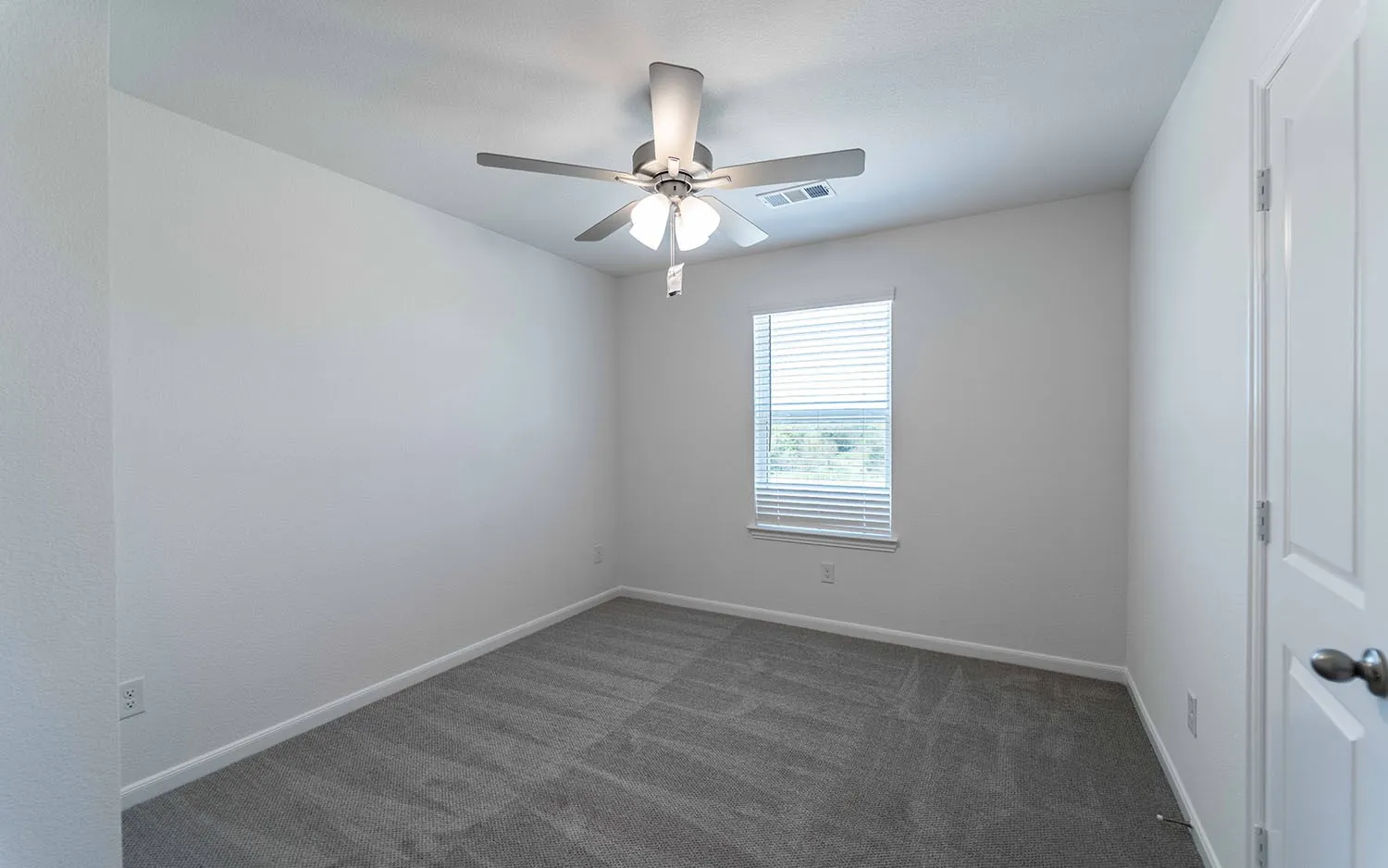 Carpeted room featuring a window with horizontal blinds, a ceiling fan with integrated lighting, and white baseboards