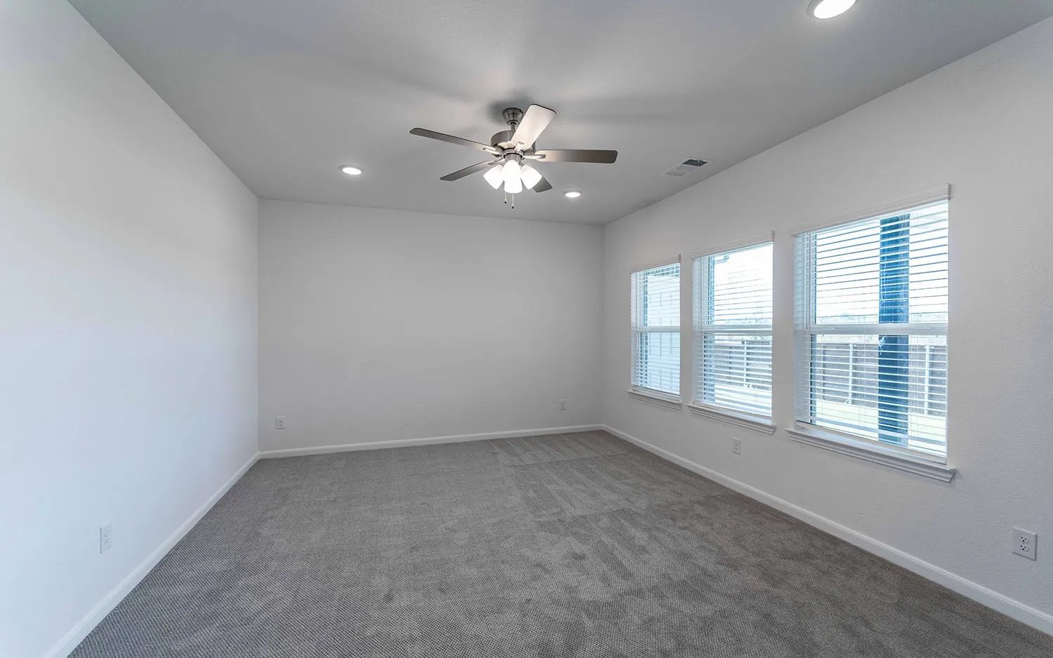 Spacious interior room with light gray carpeting and white walls