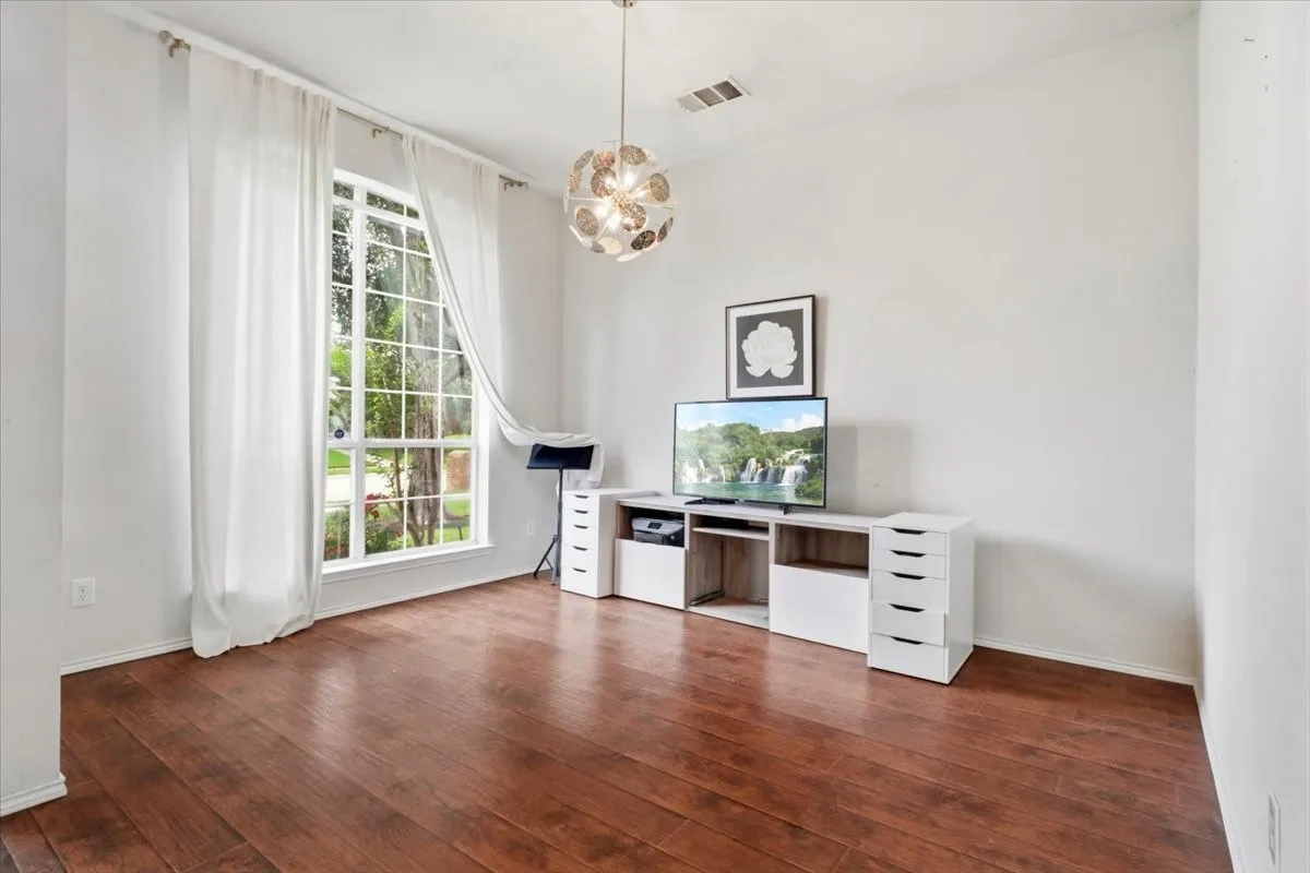 Spacious room featuring wood-finish flooring, a large multi-pane window, and a contemporary ceiling light fixture