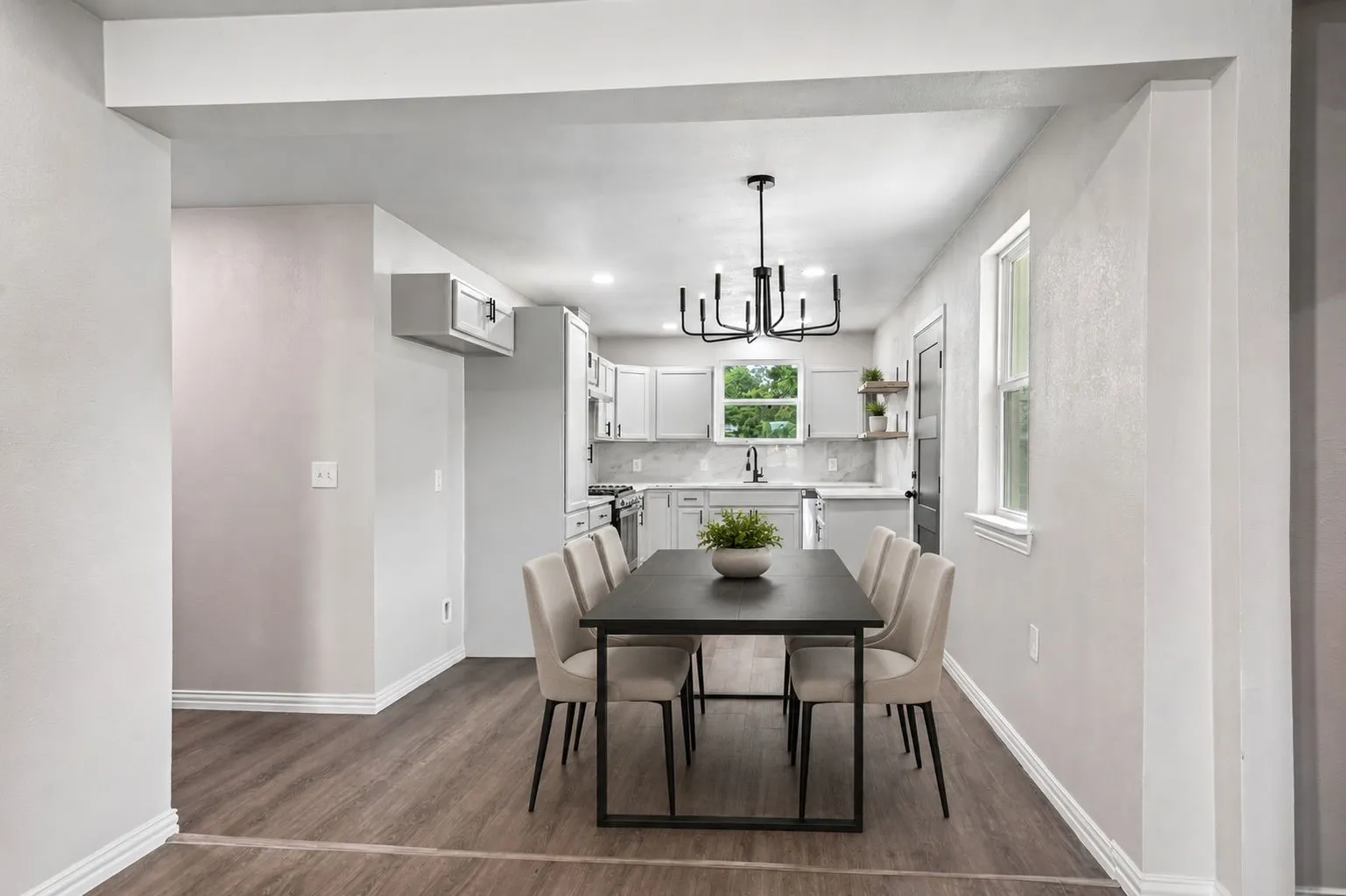 Integrated dining area featuring wood-finish flooring, a contemporary chandelier, and direct access to the kitchen