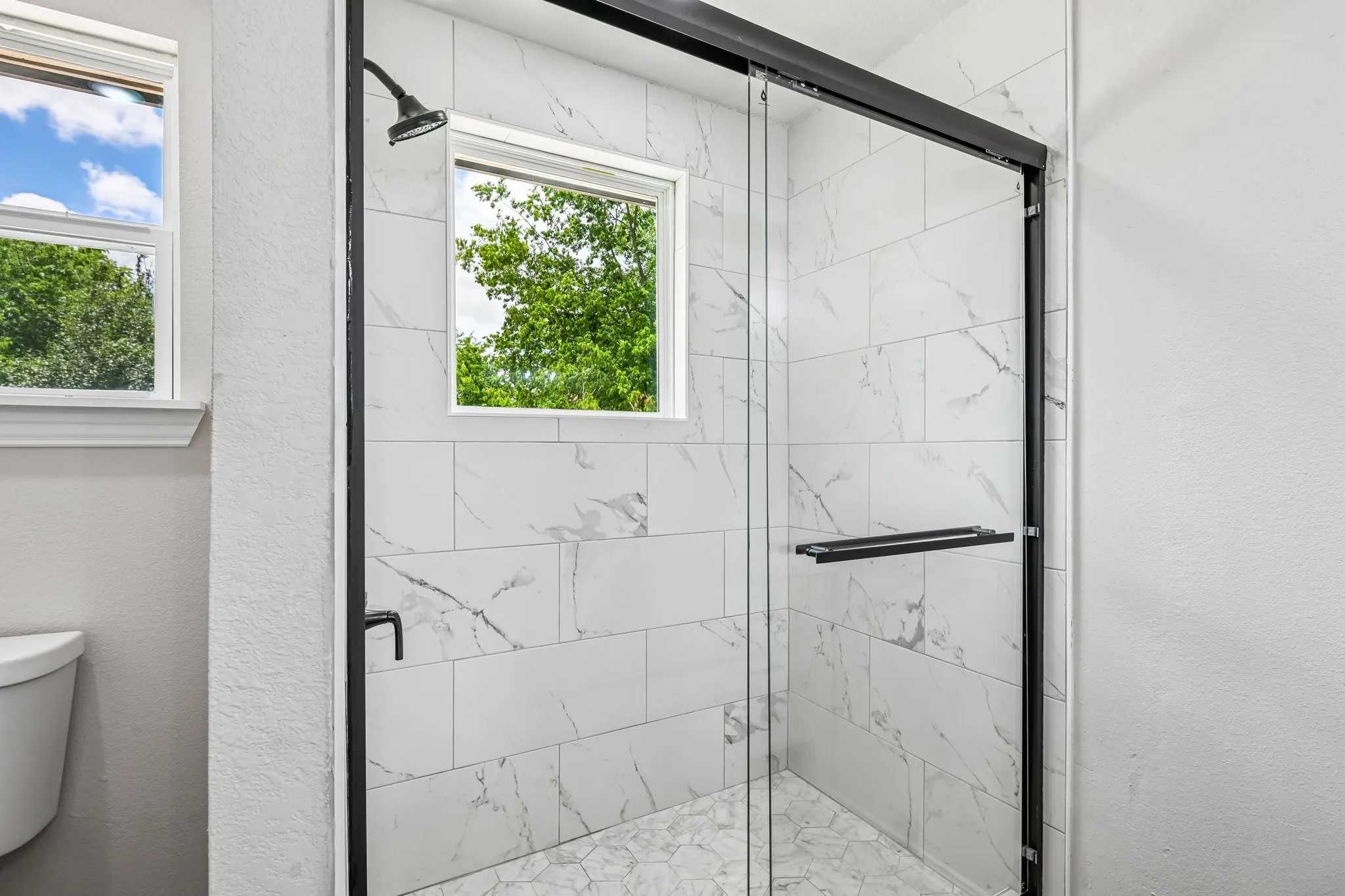 Walk-in shower with clear glass enclosure and matte black hardware