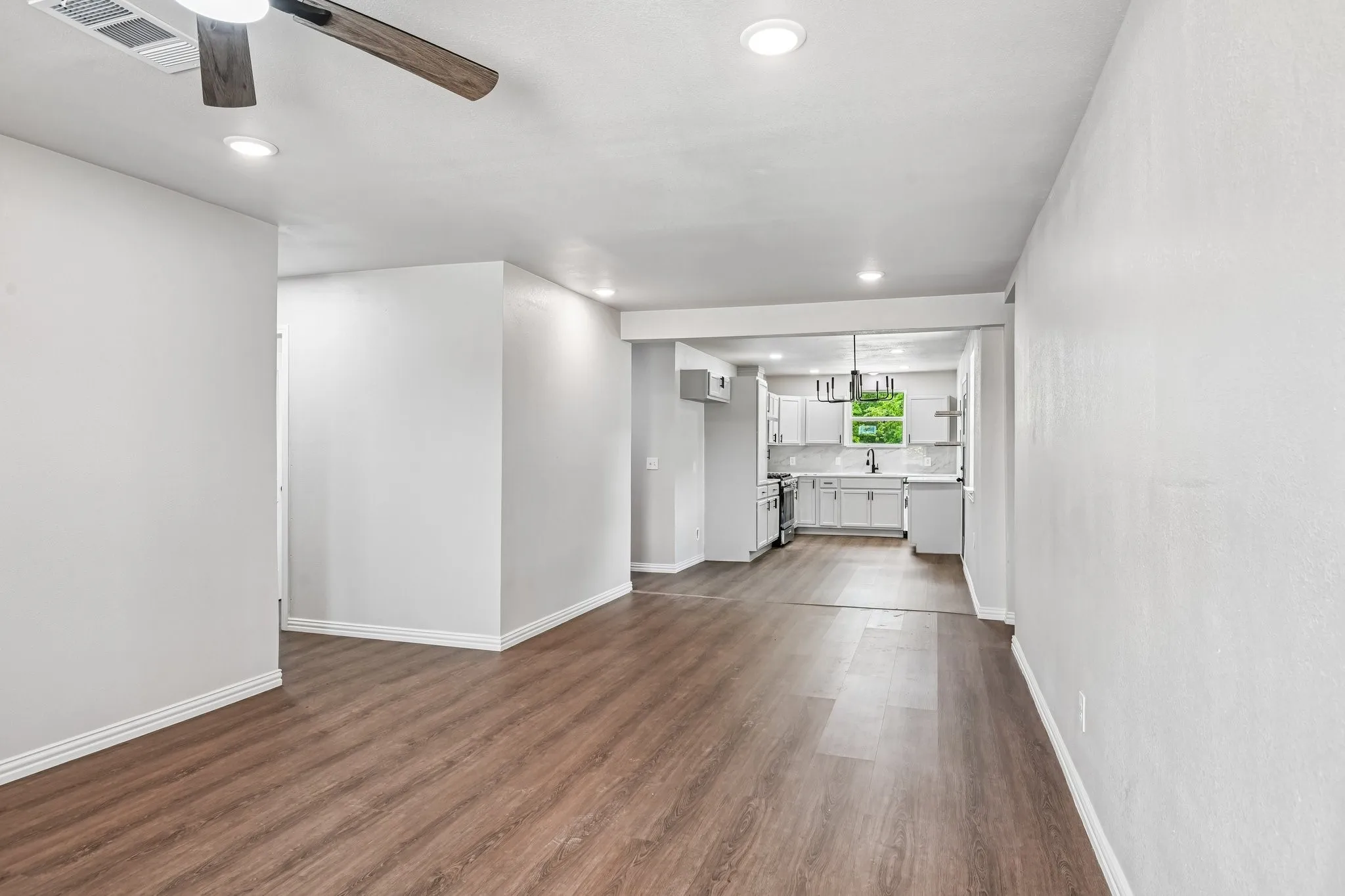 Spacious living area featuring wood-finish flooring, recessed lighting, and a ceiling fan with integrated light