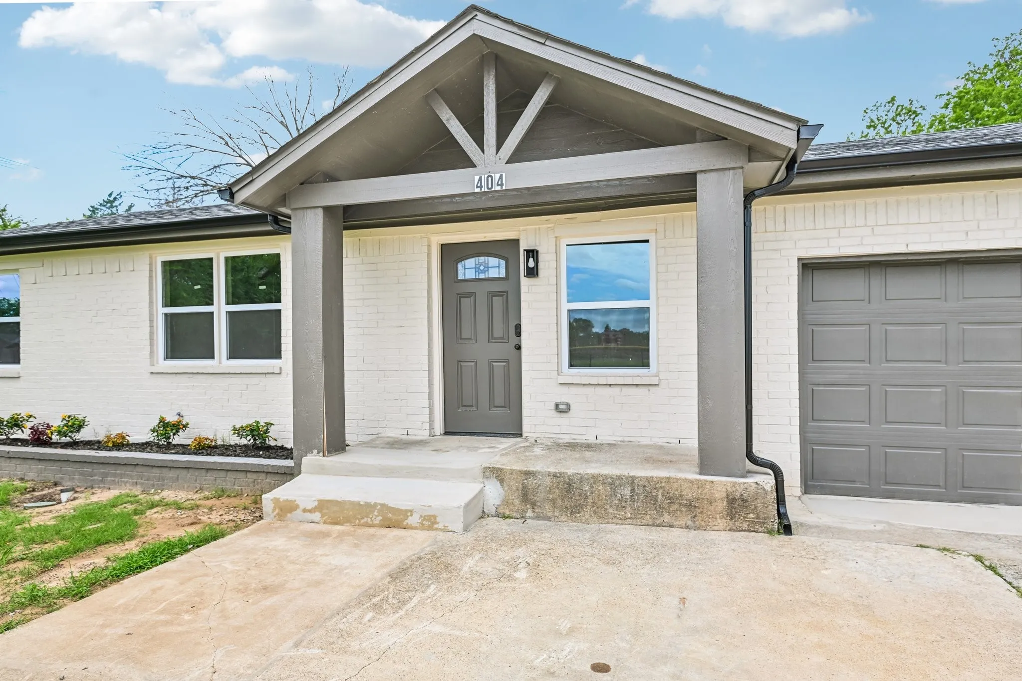 White brick exterior with a gray trim and matching front door