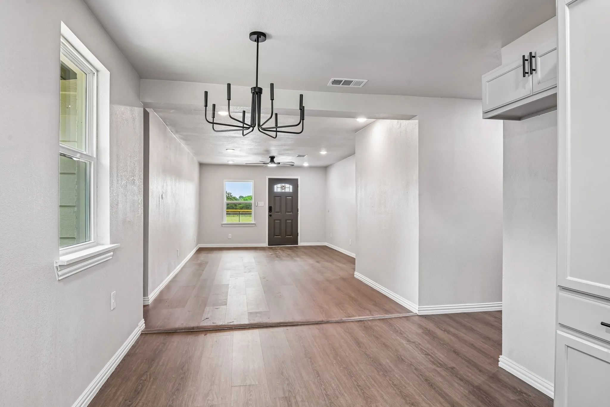 Spacious interior featuring wood-finish flooring, white trim, and a modern black chandelier