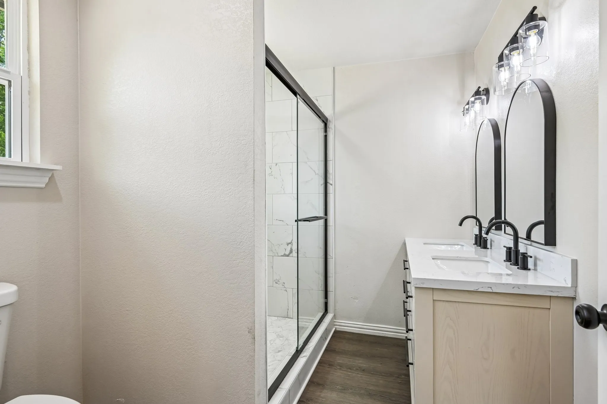 Bathroom featuring a dual vanity with rectangular sinks, black faucets, and arch-top mirrors