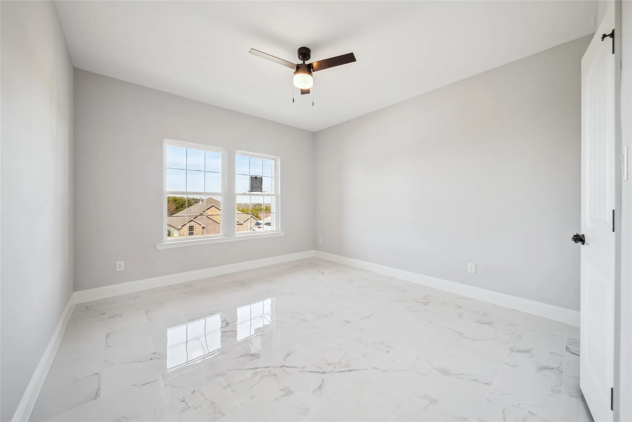 Room featuring large format white tile flooring, light gray wall paint, and white baseboards