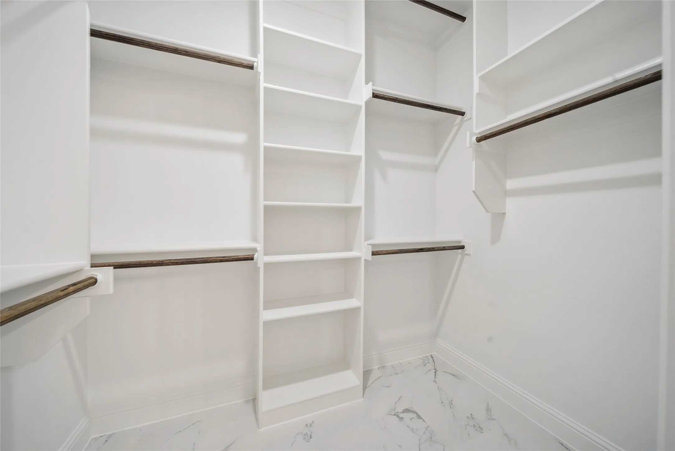 Custom closet system featuring white shelving, multiple hanging rods, and a central vertical storage unit