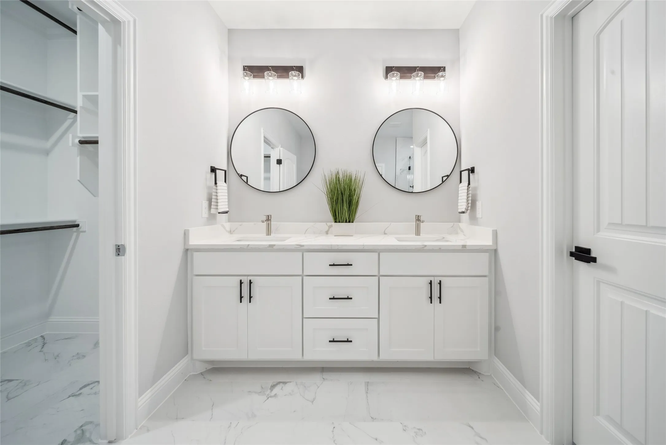 Dual vanity with white cabinetry, white countertop, and round black-framed mirrors