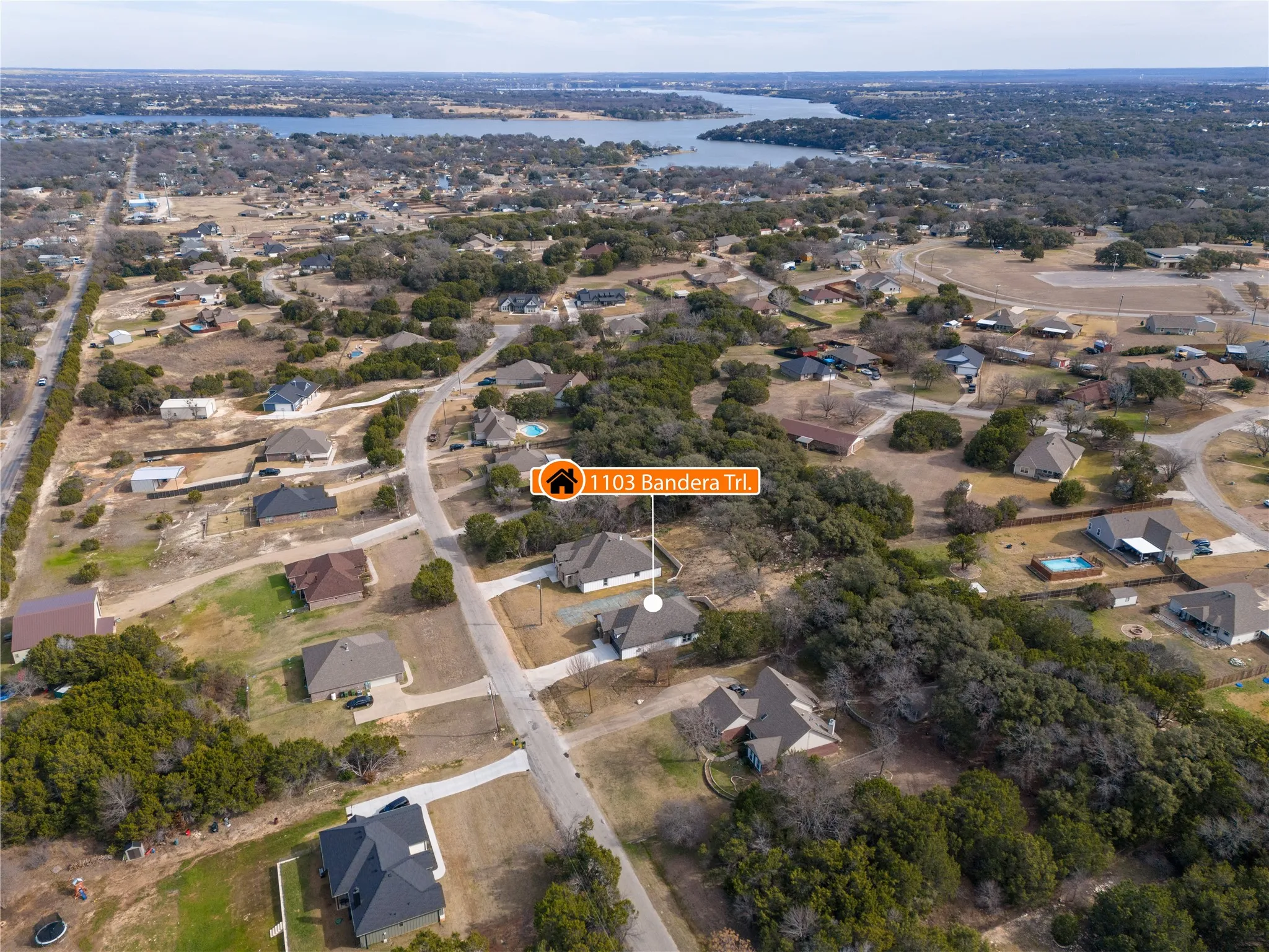 Aerial perspective showcasing the property at 1103 Bandera Trl within a residential neighborhood featuring mature trees and established homes