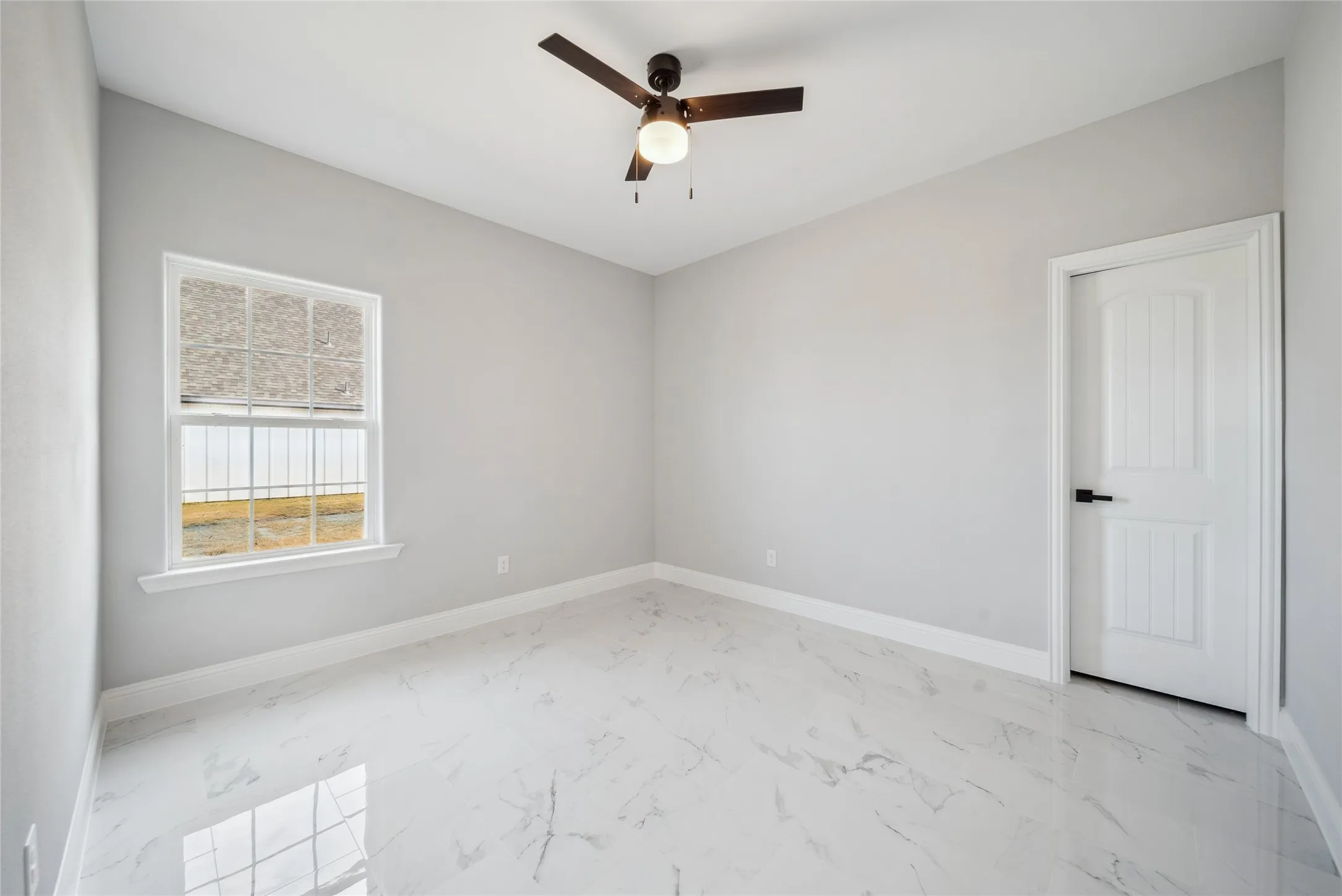 Room featuring large-format porcelain tile flooring, a multi-pane window, and a ceiling fan with integrated lighting