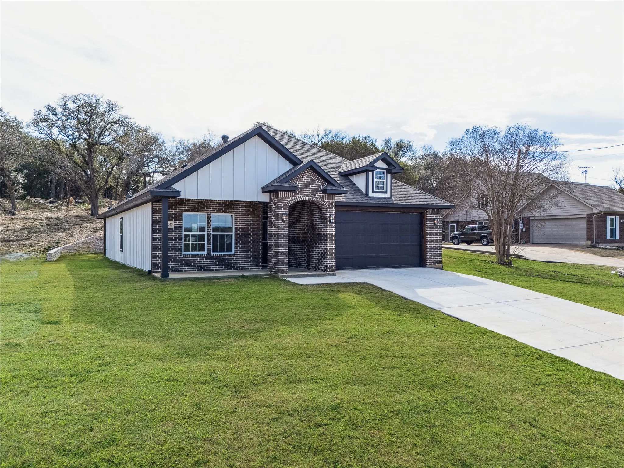 Contemporary brick and vertical siding exterior with a dark gray garage door