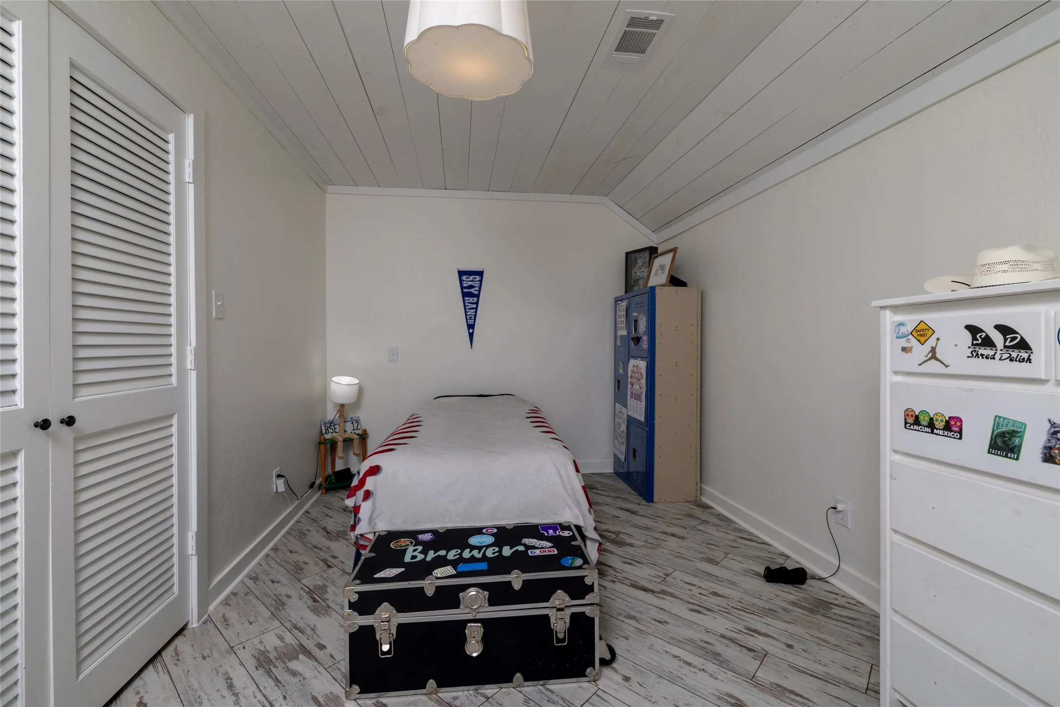 Attic room featuring white wood-finish flooring, white horizontal plank ceiling, and white louvered double doors