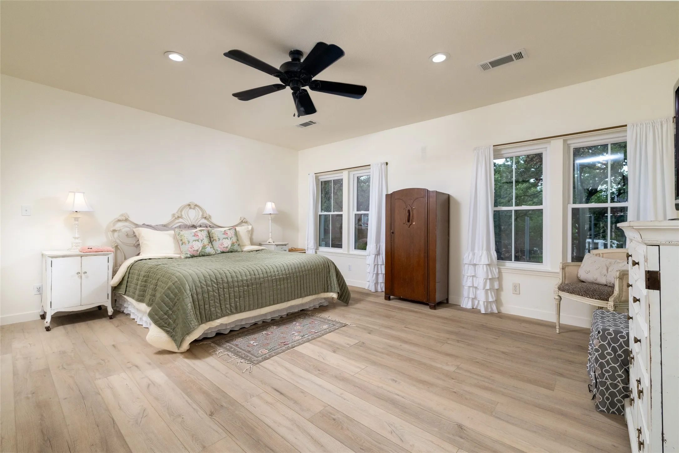 Spacious room featuring light wood-finish flooring, recessed lighting, and a ceiling fan