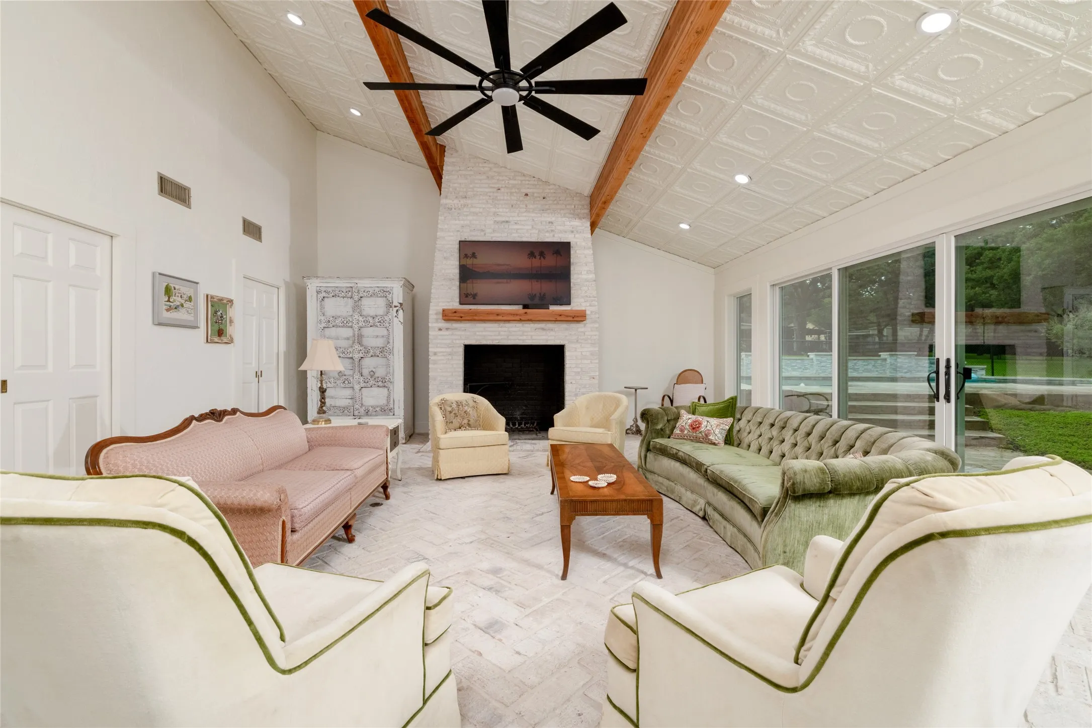 Spacious living area featuring a vaulted ceiling with decorative ceiling tiles, exposed wood beams, and recessed lighting