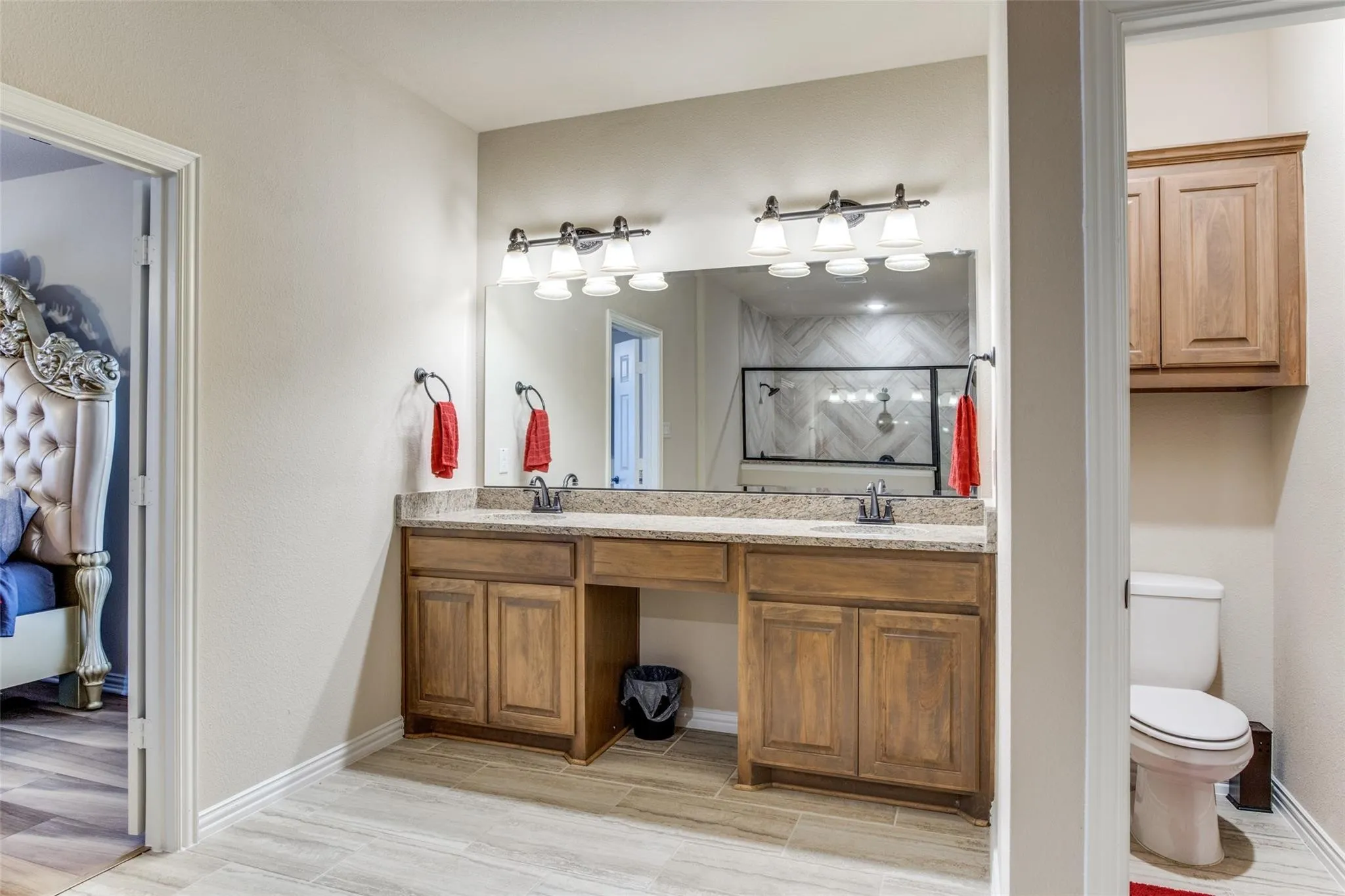 Primary Bathroom featuring a double vanity with wood cabinetry, granite-finish countertop, and undermount sinks
