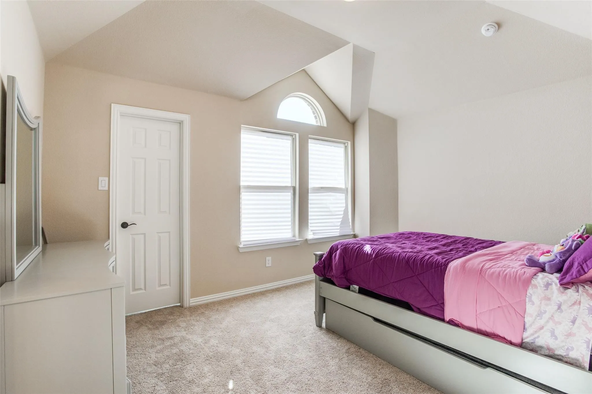 Carpeted room featuring a vaulted ceiling and an arched window
